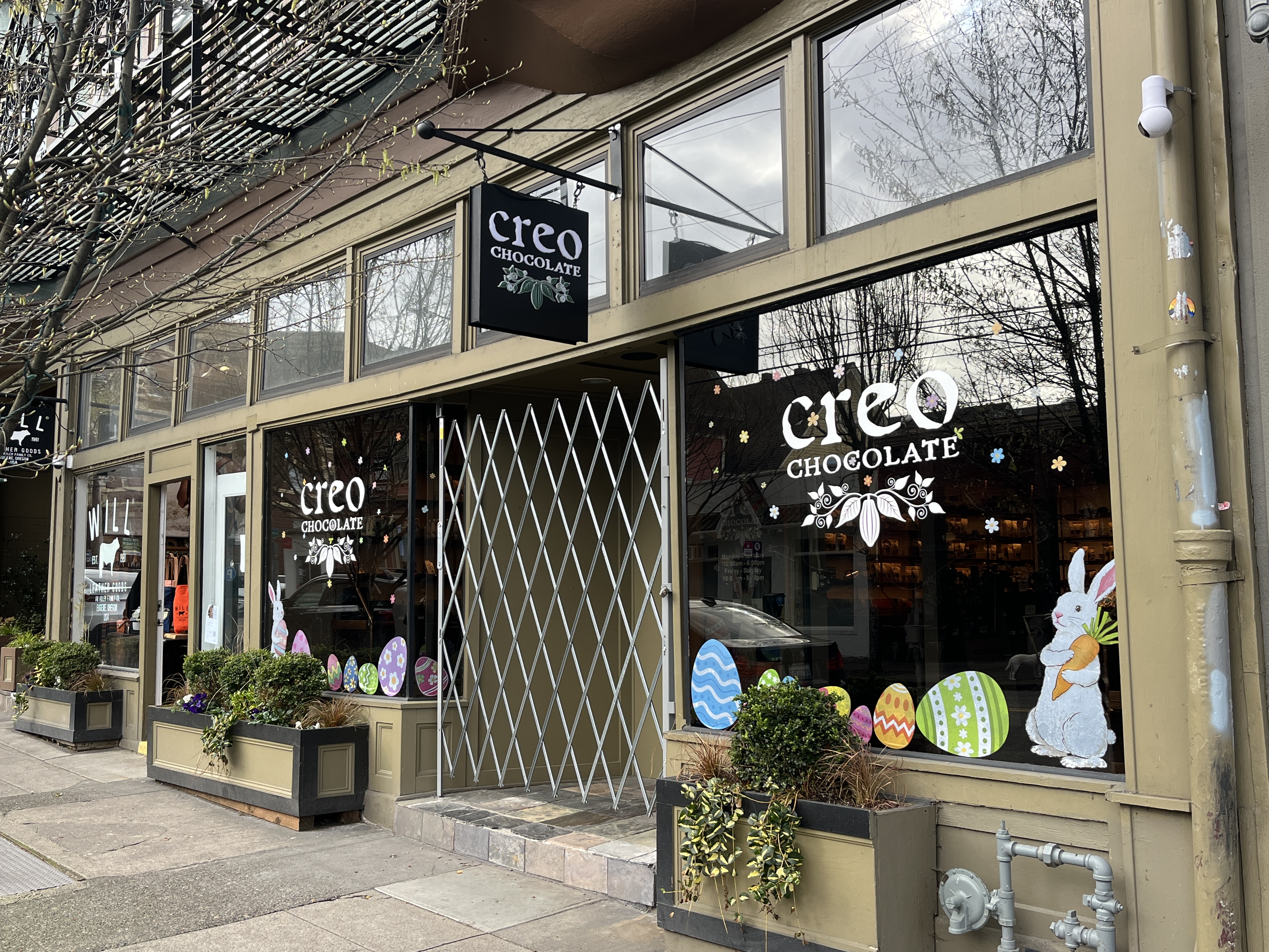 Exterior of a Creo Chocolate shop with hanging sign and decorated windows.