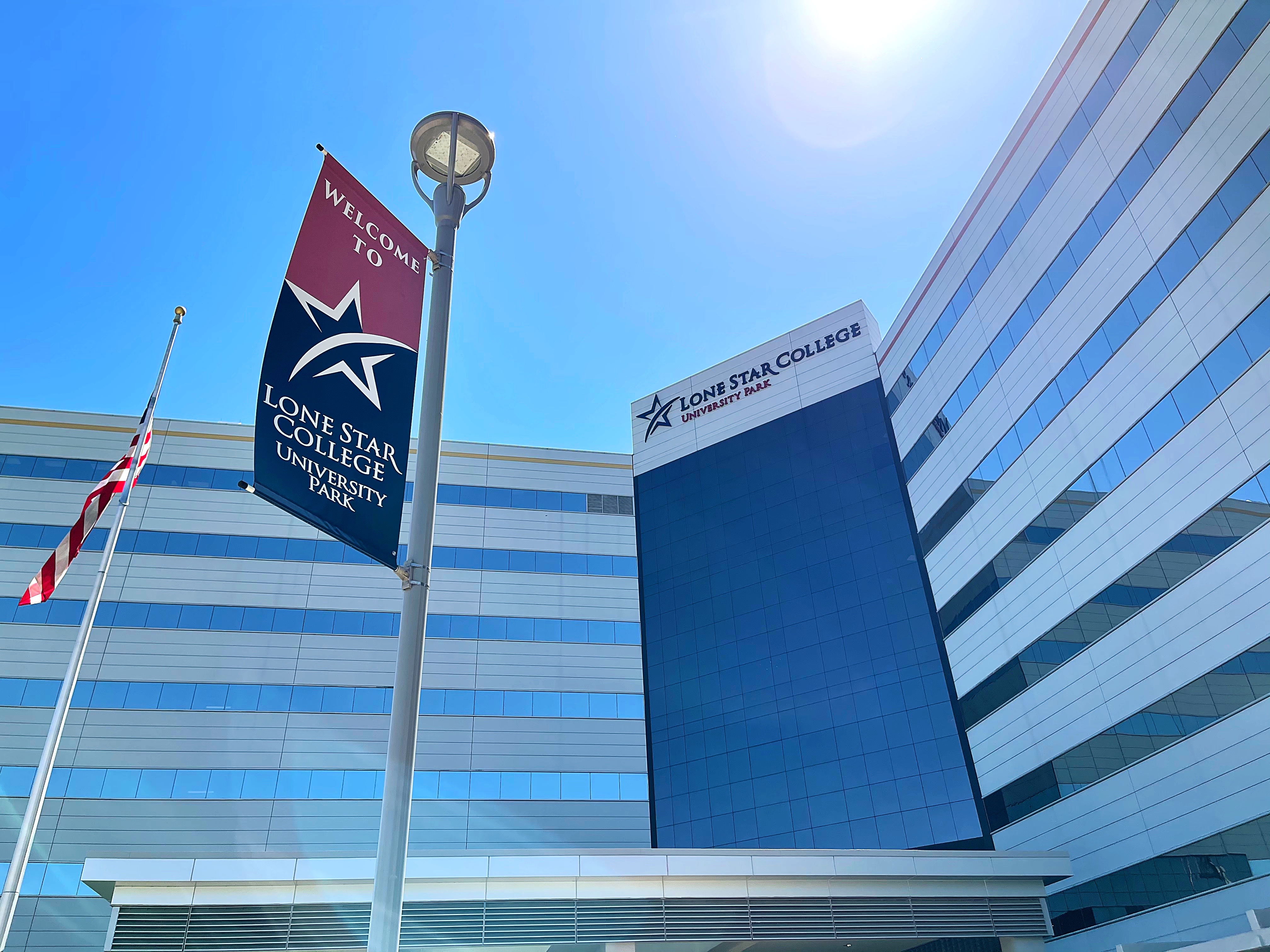 Exterior of a glass college building with a welcome banner and college logo on the facade.