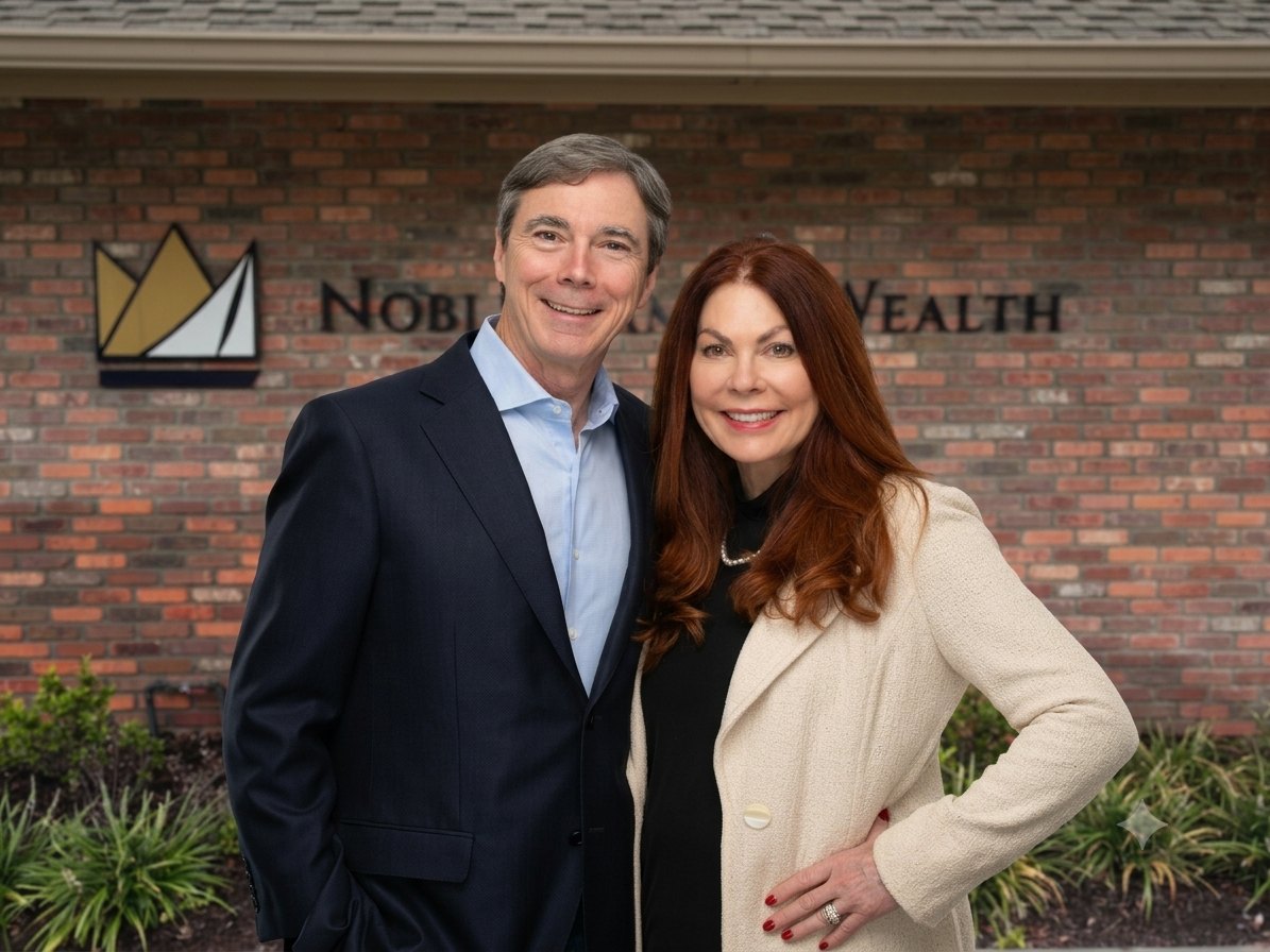 A man and woman smile in front of a brick building with a Noble Family Wealth sign.