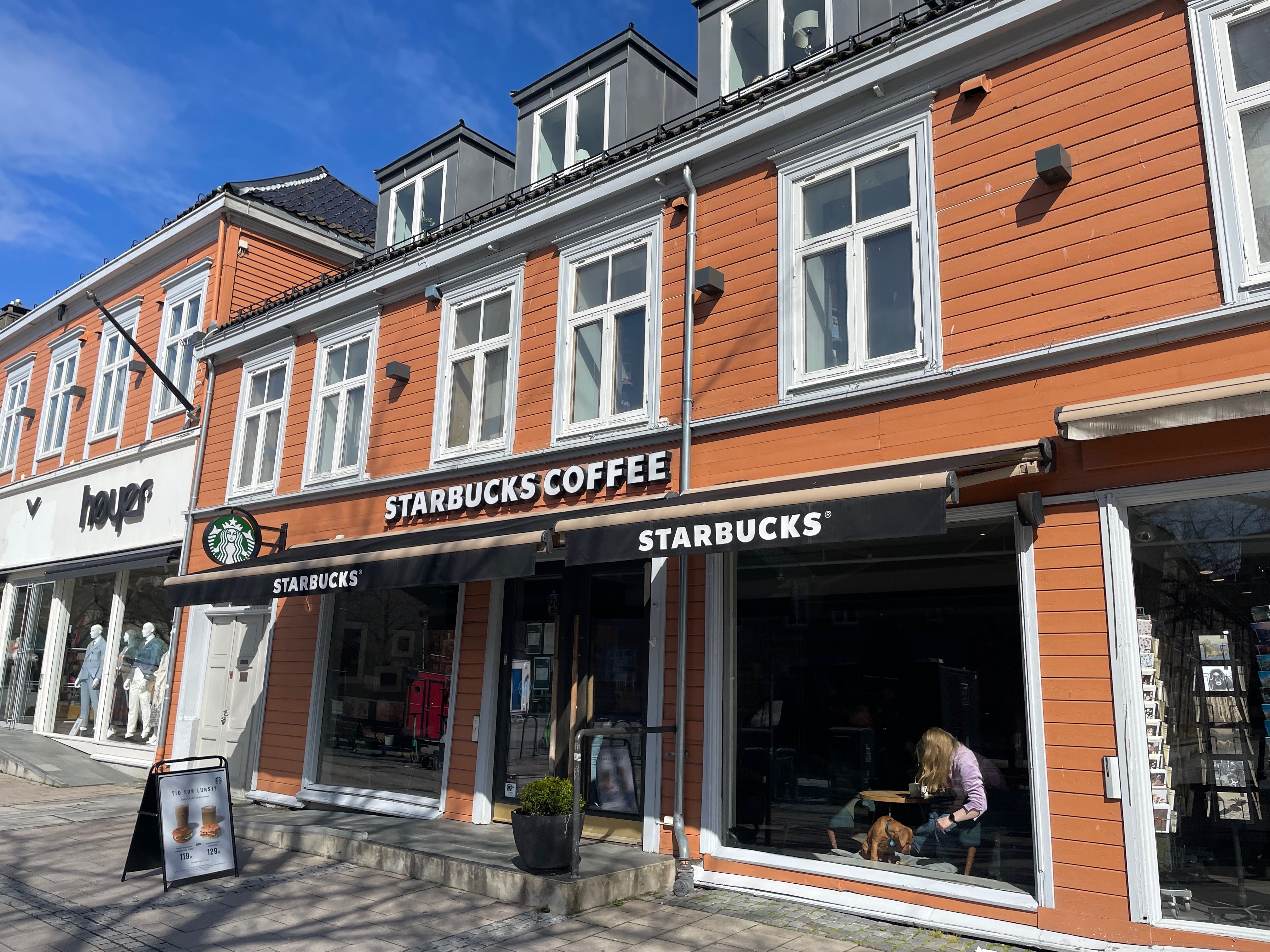 Exterior of a Starbucks Coffee shop with green-and-white signage on a city street.