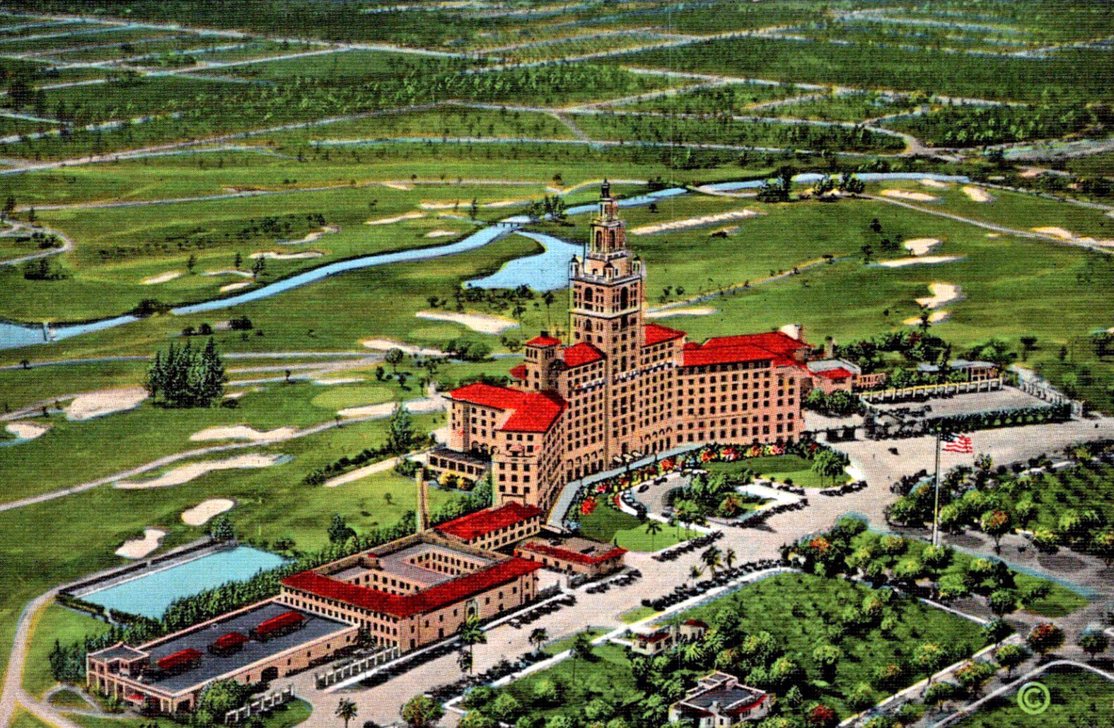 Aerial postcard view of a large hotel and surrounding golf course with sand bunkers.