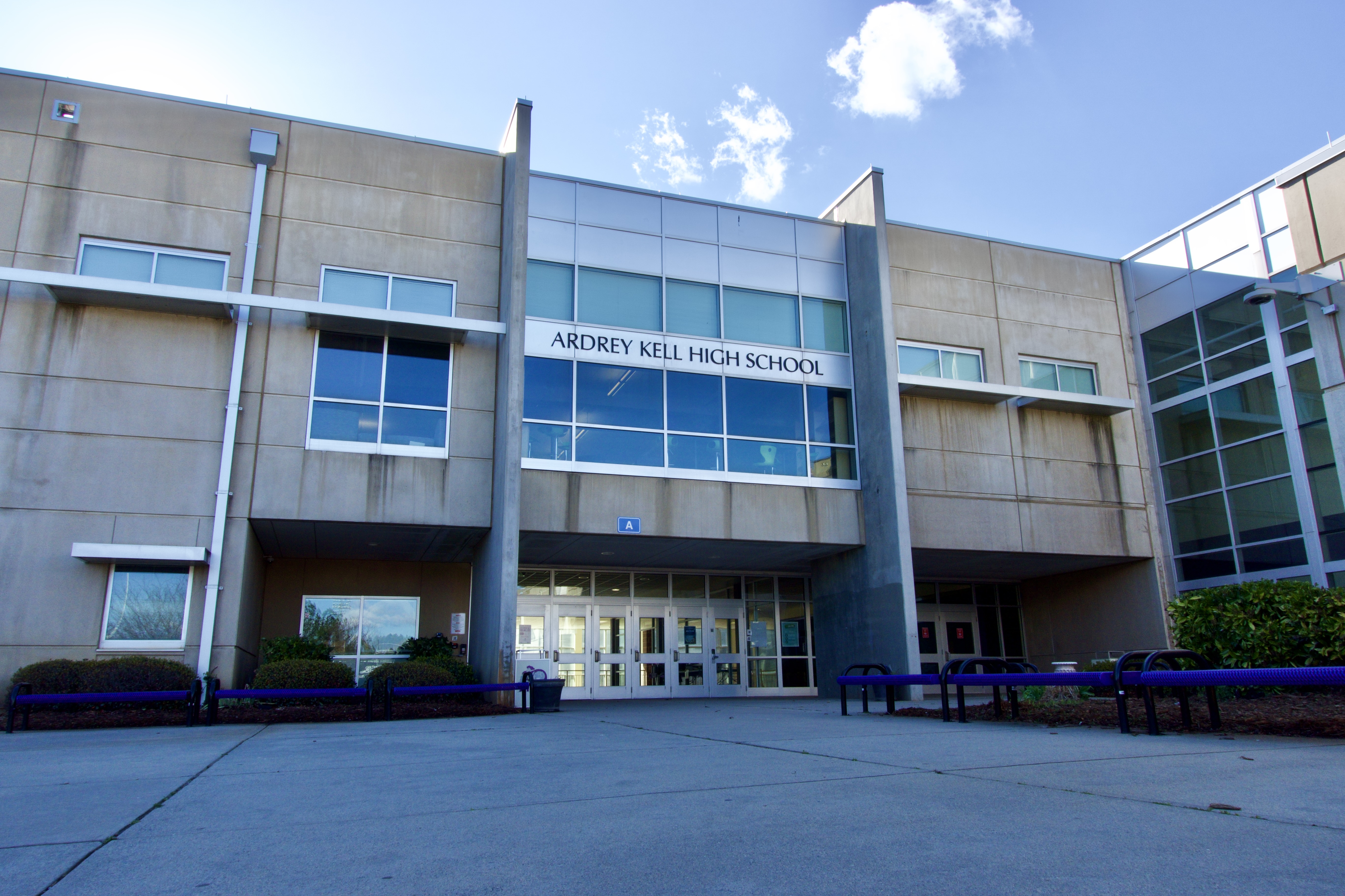Entrance of a modern high school building with the school name above glass doors.