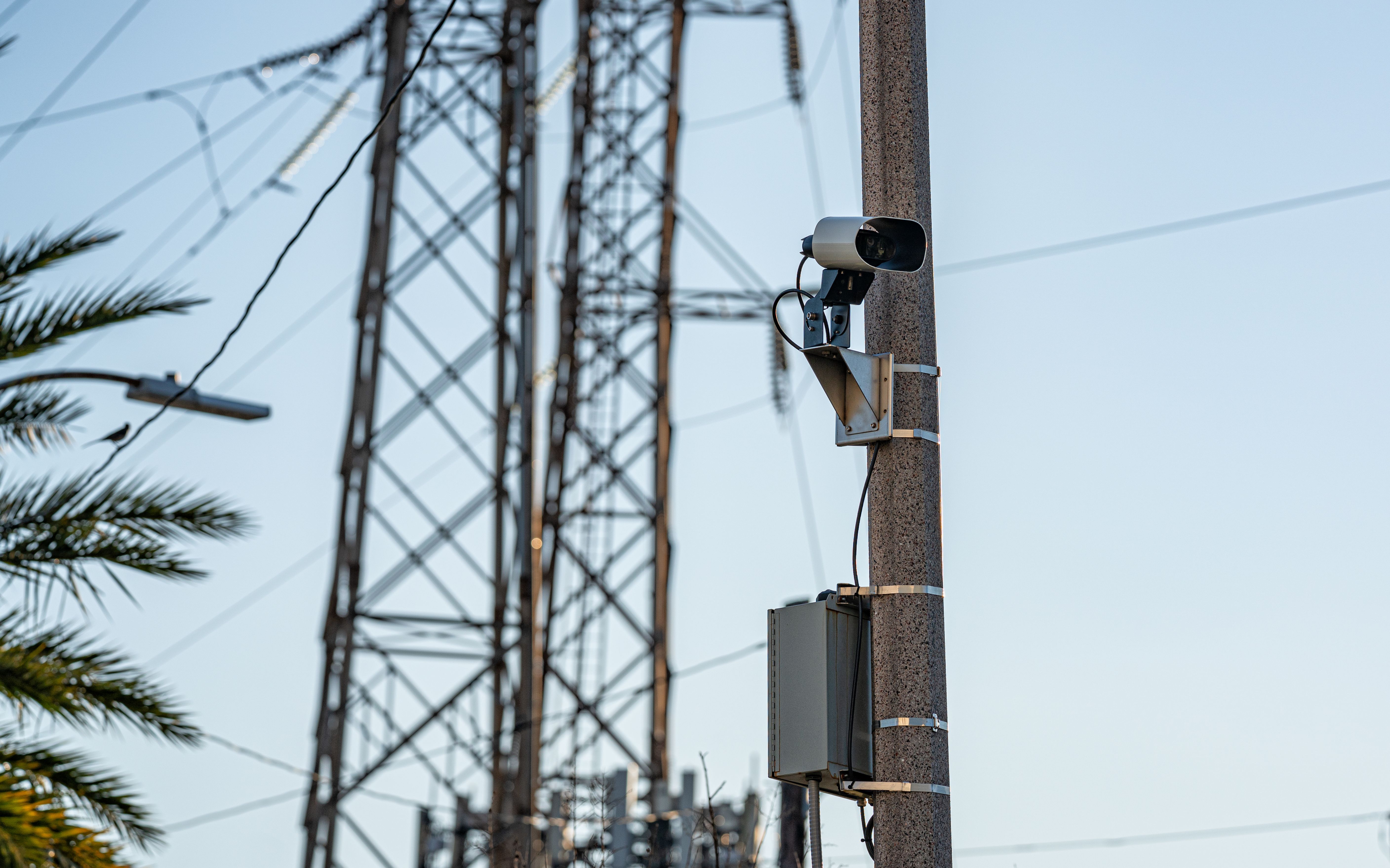 A white automated license plate reader camera mounted on a utility pole outdoors.