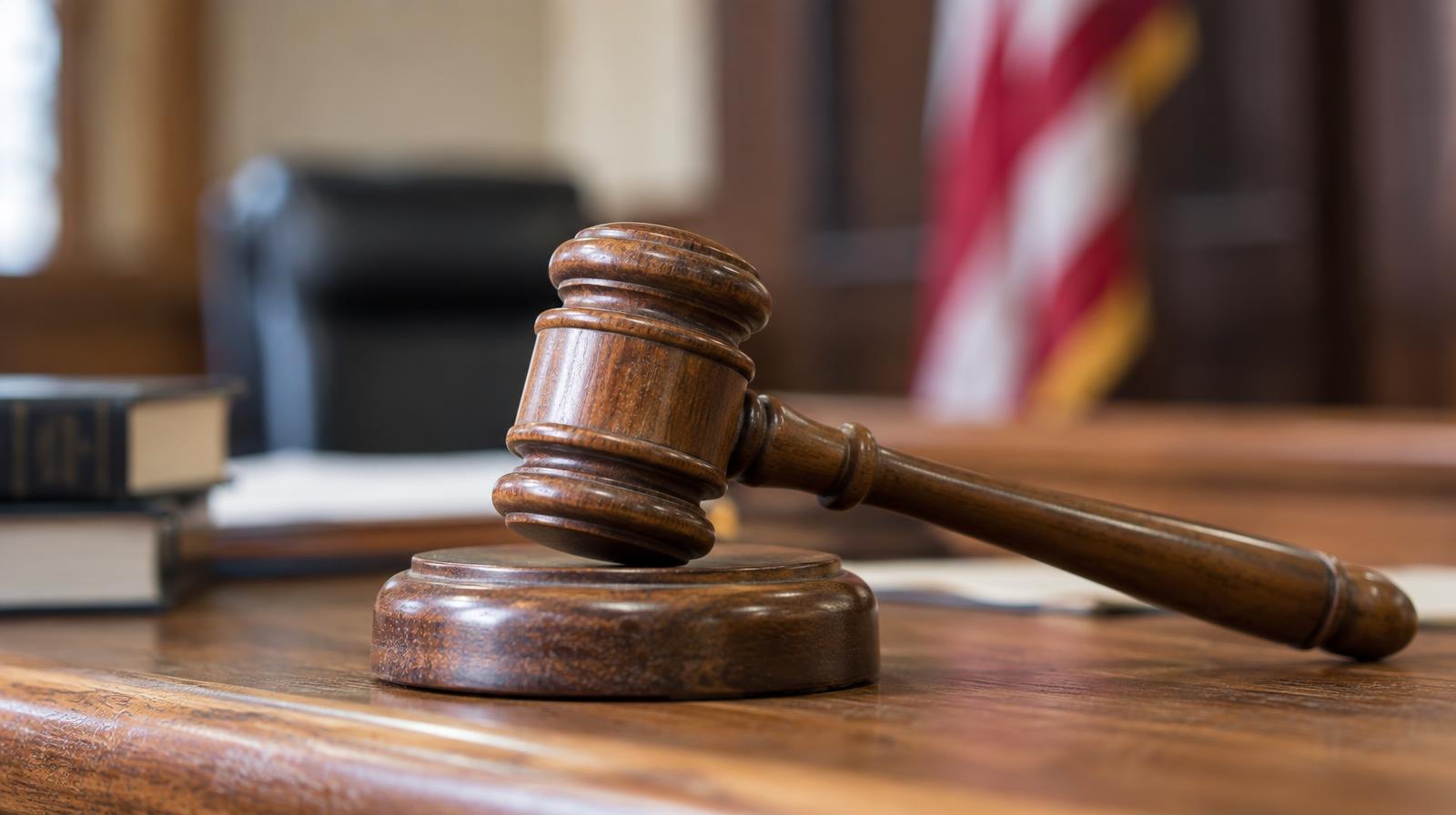 Wooden judge's gavel resting on its sound block on a bench.