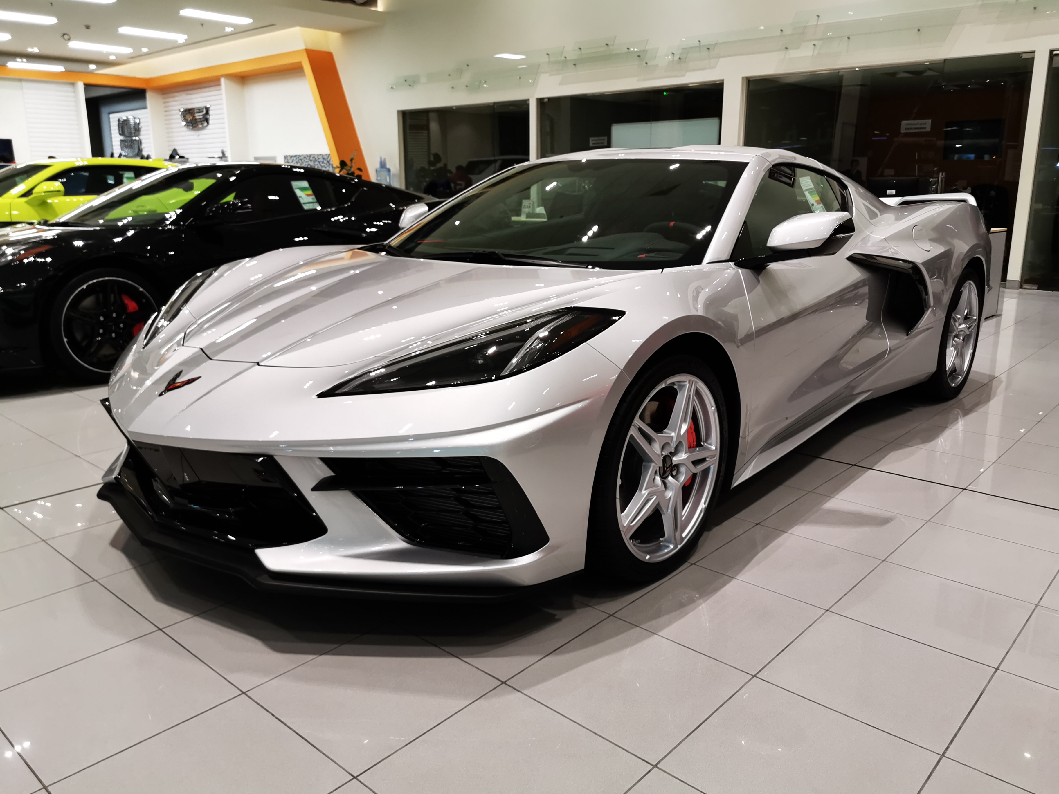 Silver sports car displayed inside a brightly lit car dealership showroom.