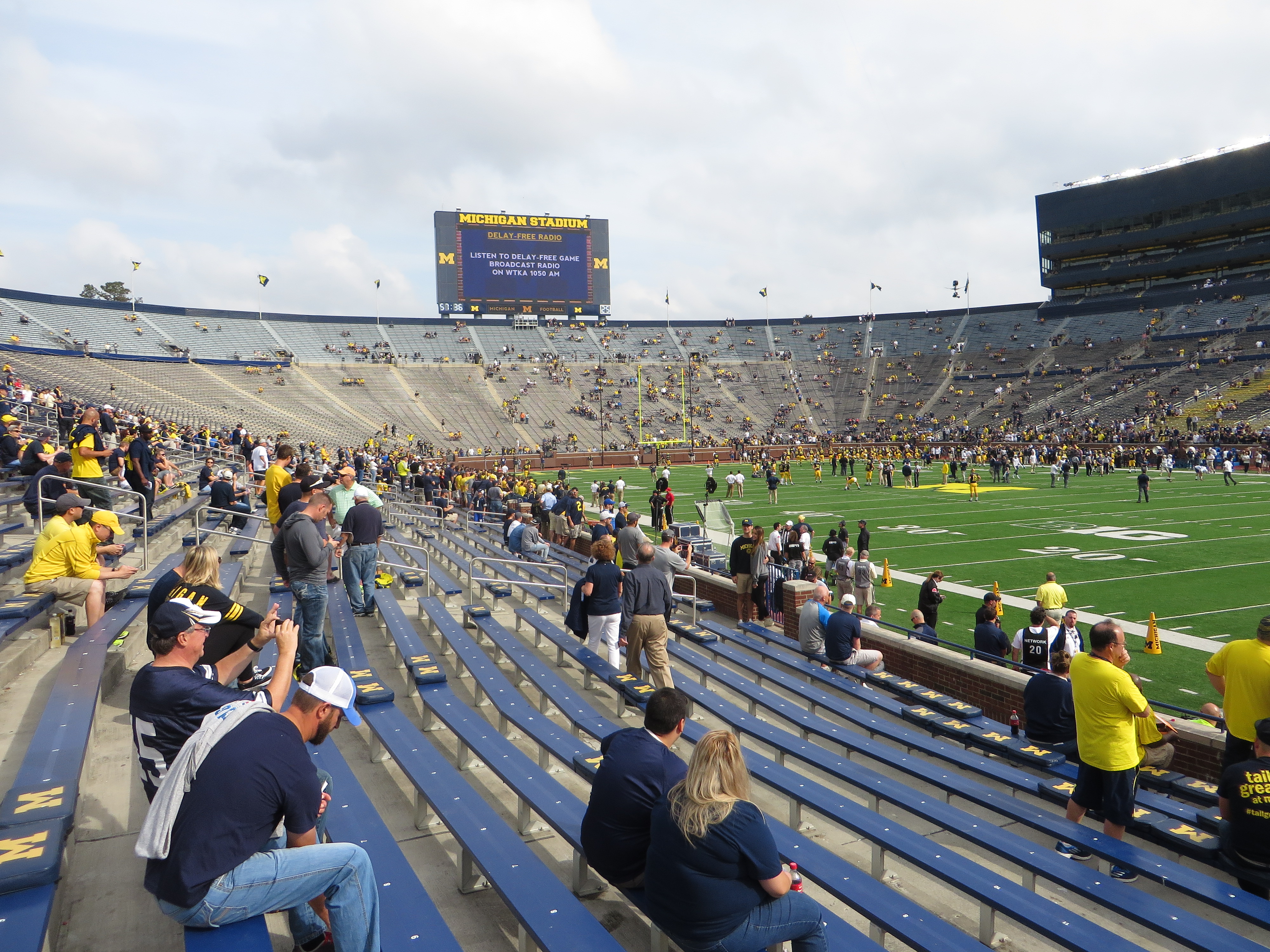 Interior of a large football stadium showing the field, blue seating bowl, and scoreboard.