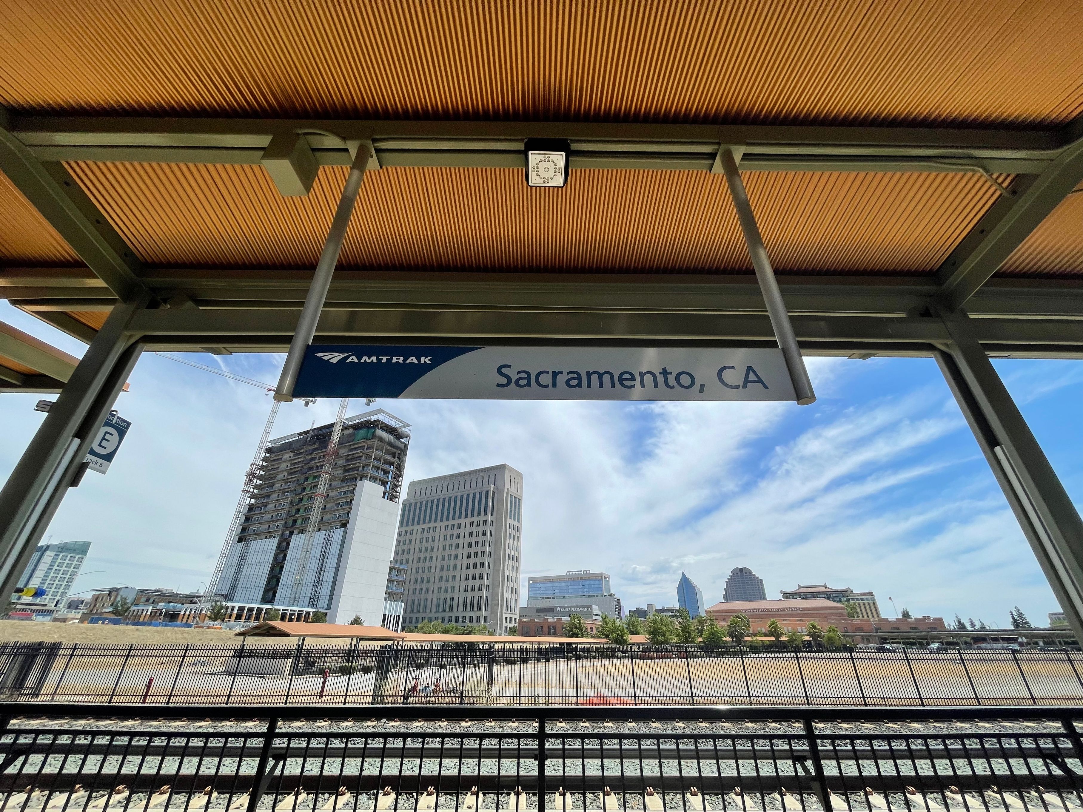 Amtrak platform canopy with a Sacramento, CA sign and city skyline visible behind