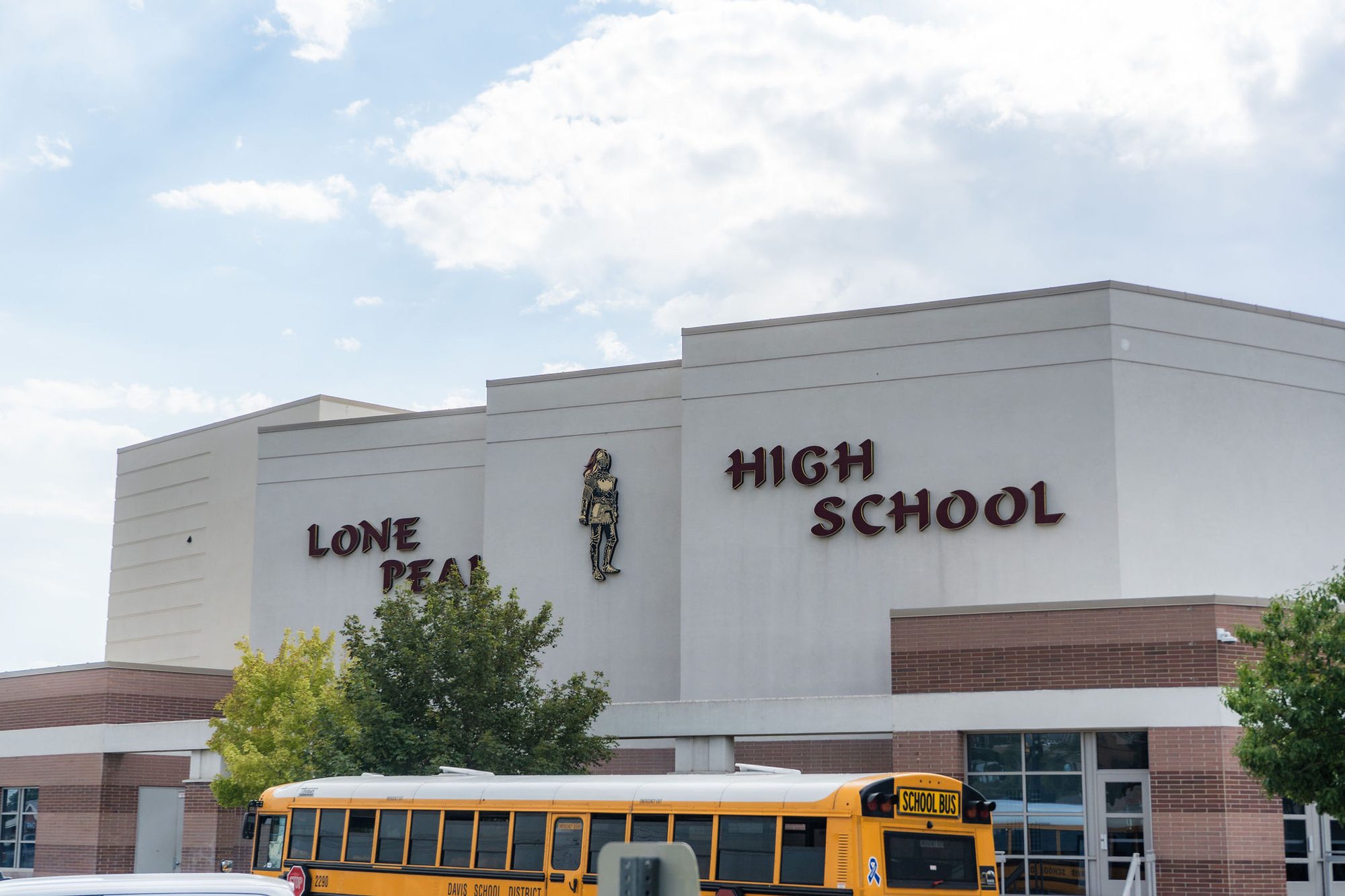 Exterior of a high school building with a yellow school bus parked outside.
