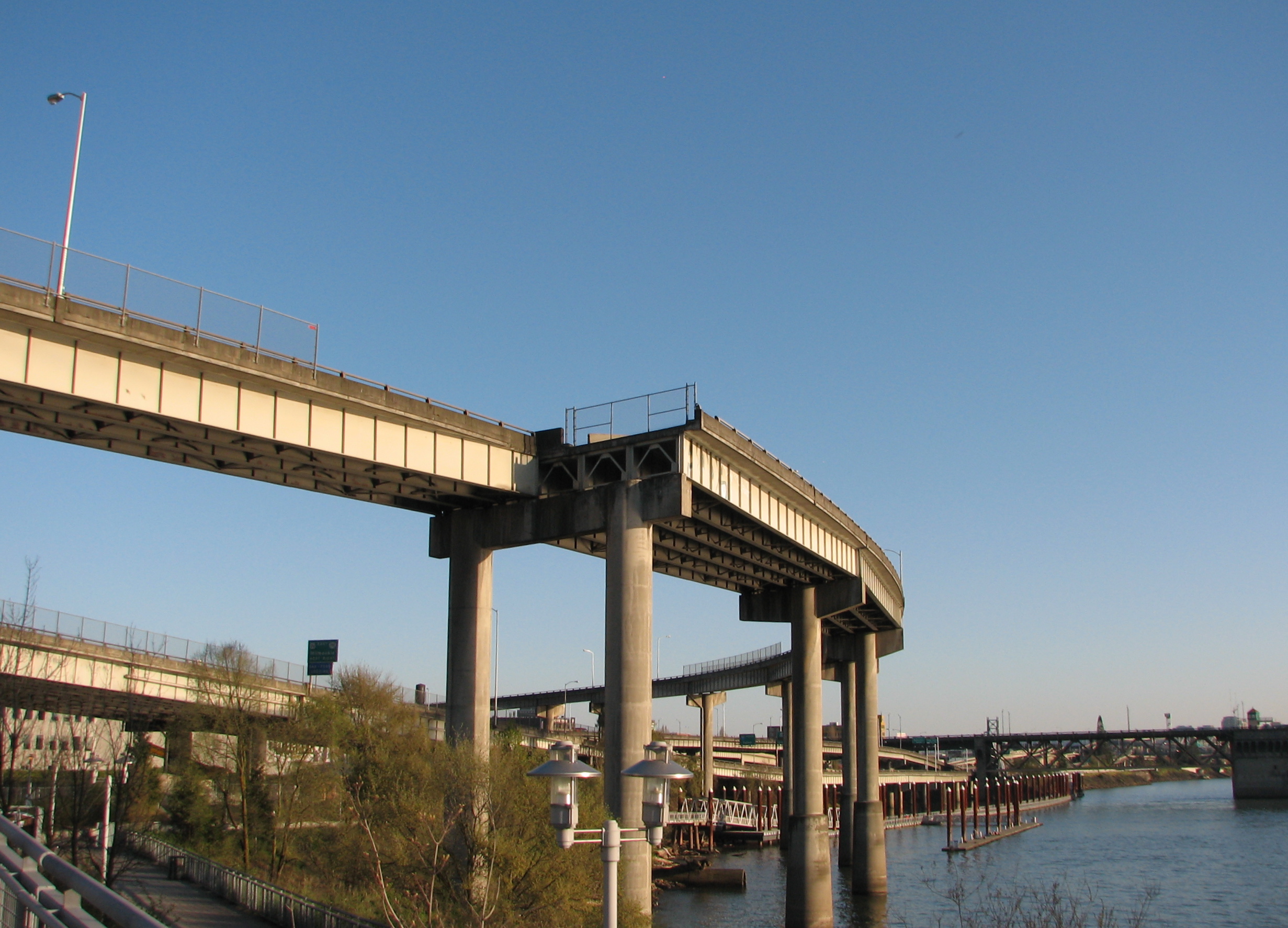 Elevated concrete freeway ramp and interchange over a river on a clear day.