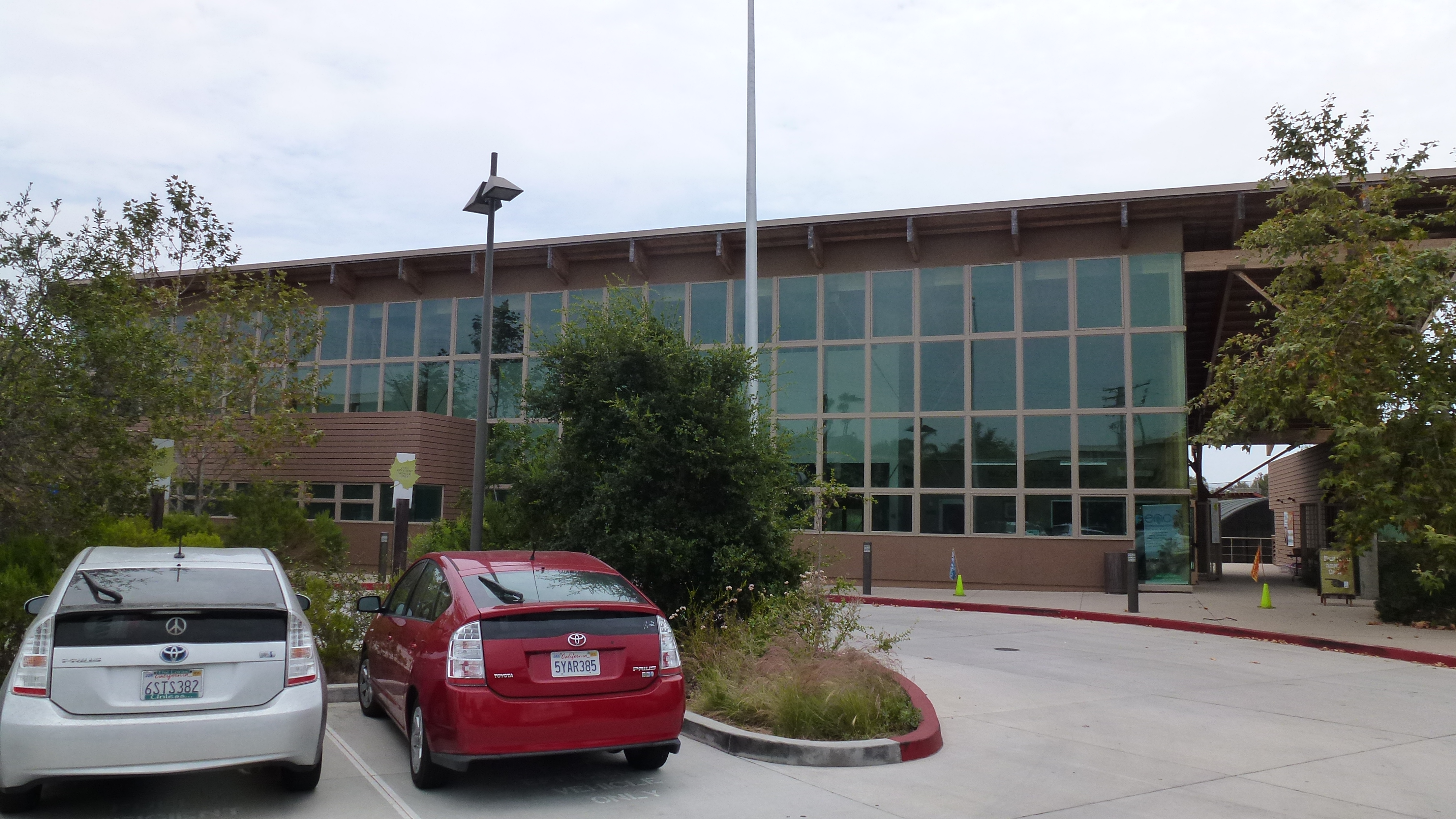 Exterior of a modern building with large glass windows and a flagpole.