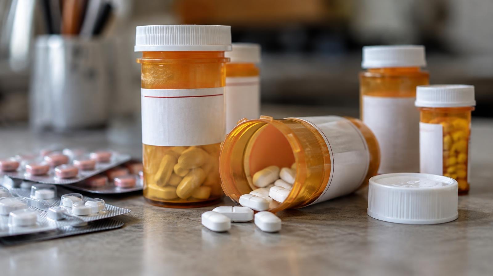 Amber prescription pill bottles and blister packs of tablets arranged on a surface.