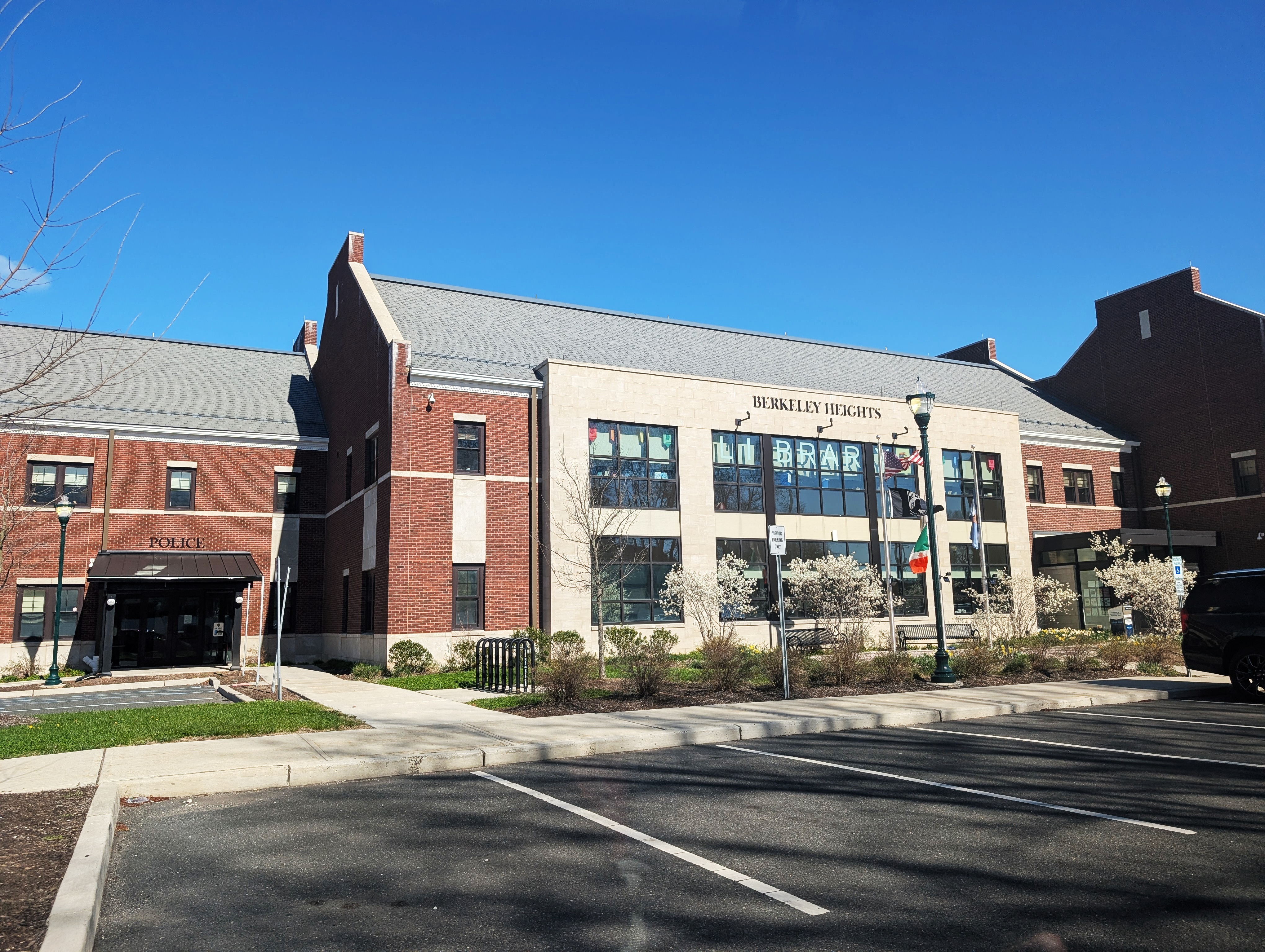 Red brick municipal building with police and library entrances under a clear blue sky.