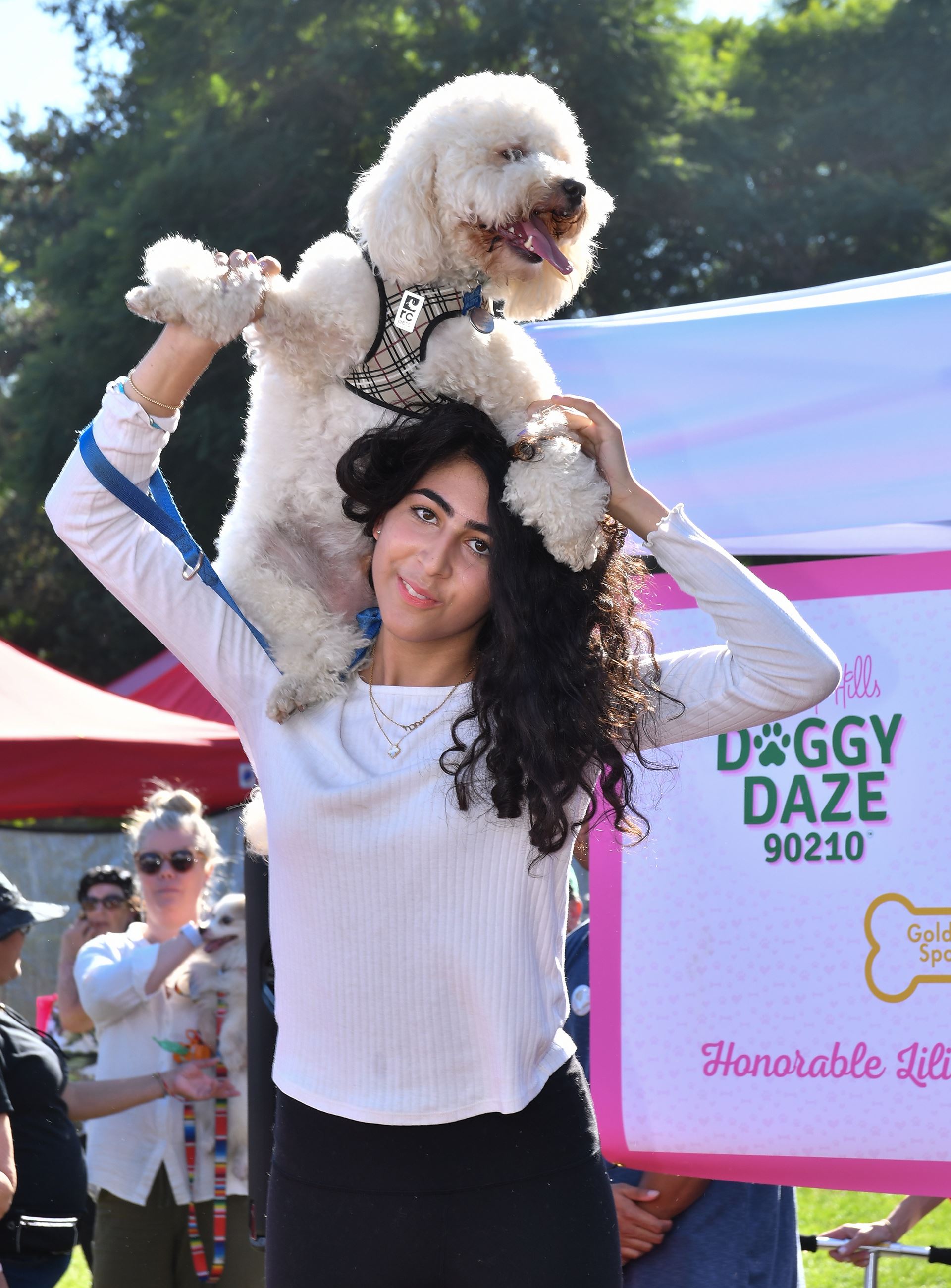 a woman holds a dog over her head