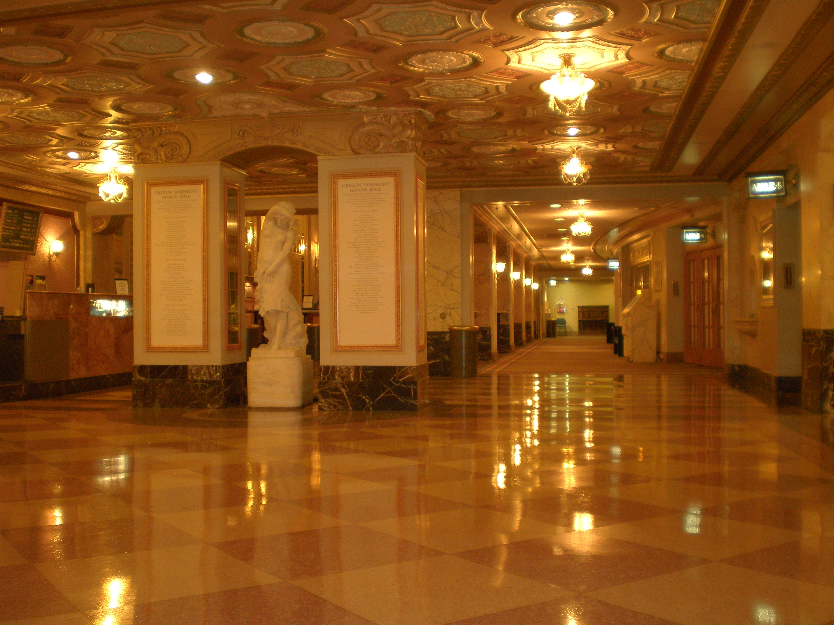 Ornate concert hall lobby with marble floors, gilded ceiling, and classical statue