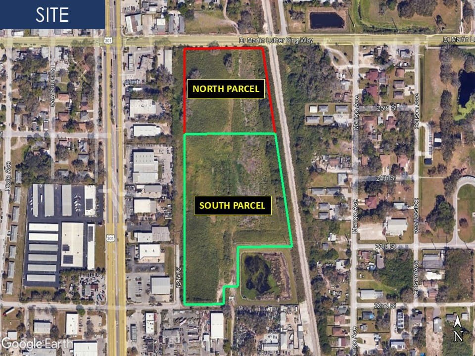 Aerial satellite view of a vacant lot divided into two outlined parcels surrounded by a residential neighborhood.