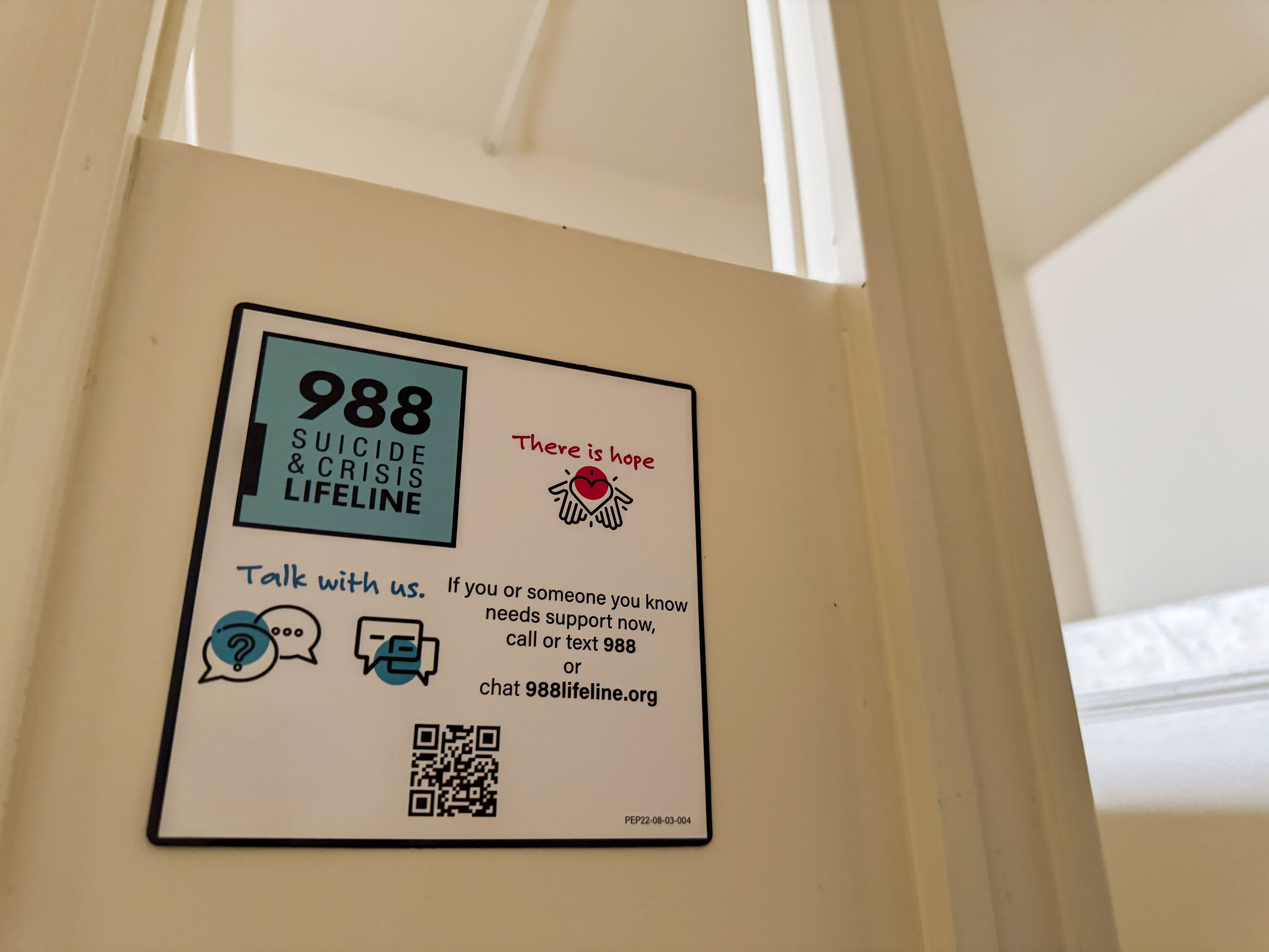 A sticker reading '988 Suicide and Crisis Lifeline — There is hope' affixed to a door.