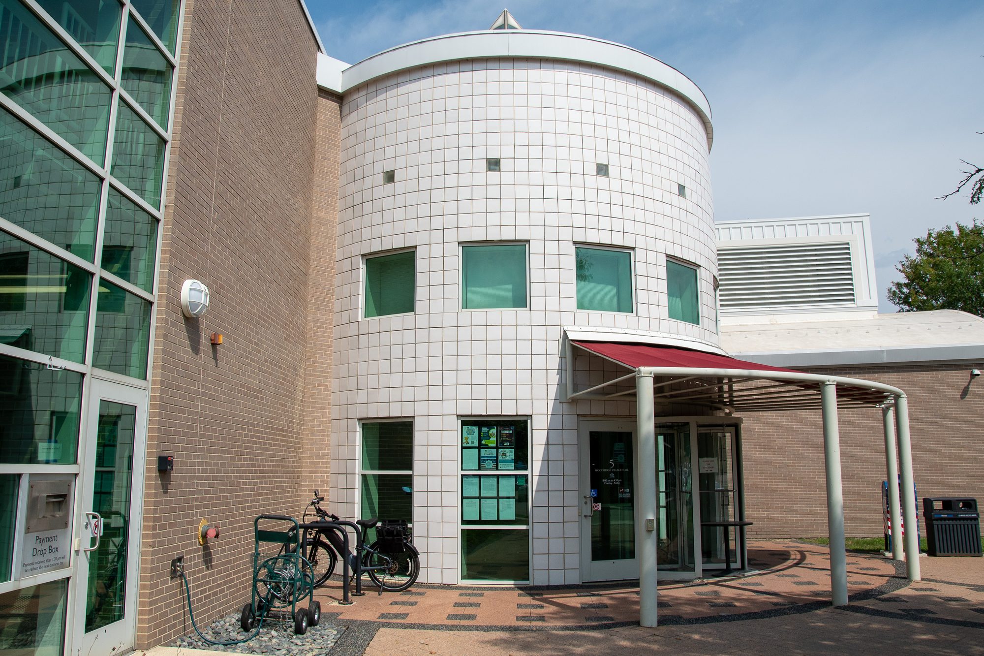 Curved white-tiled civic building with a covered entrance canopy and bicycles parked outside.