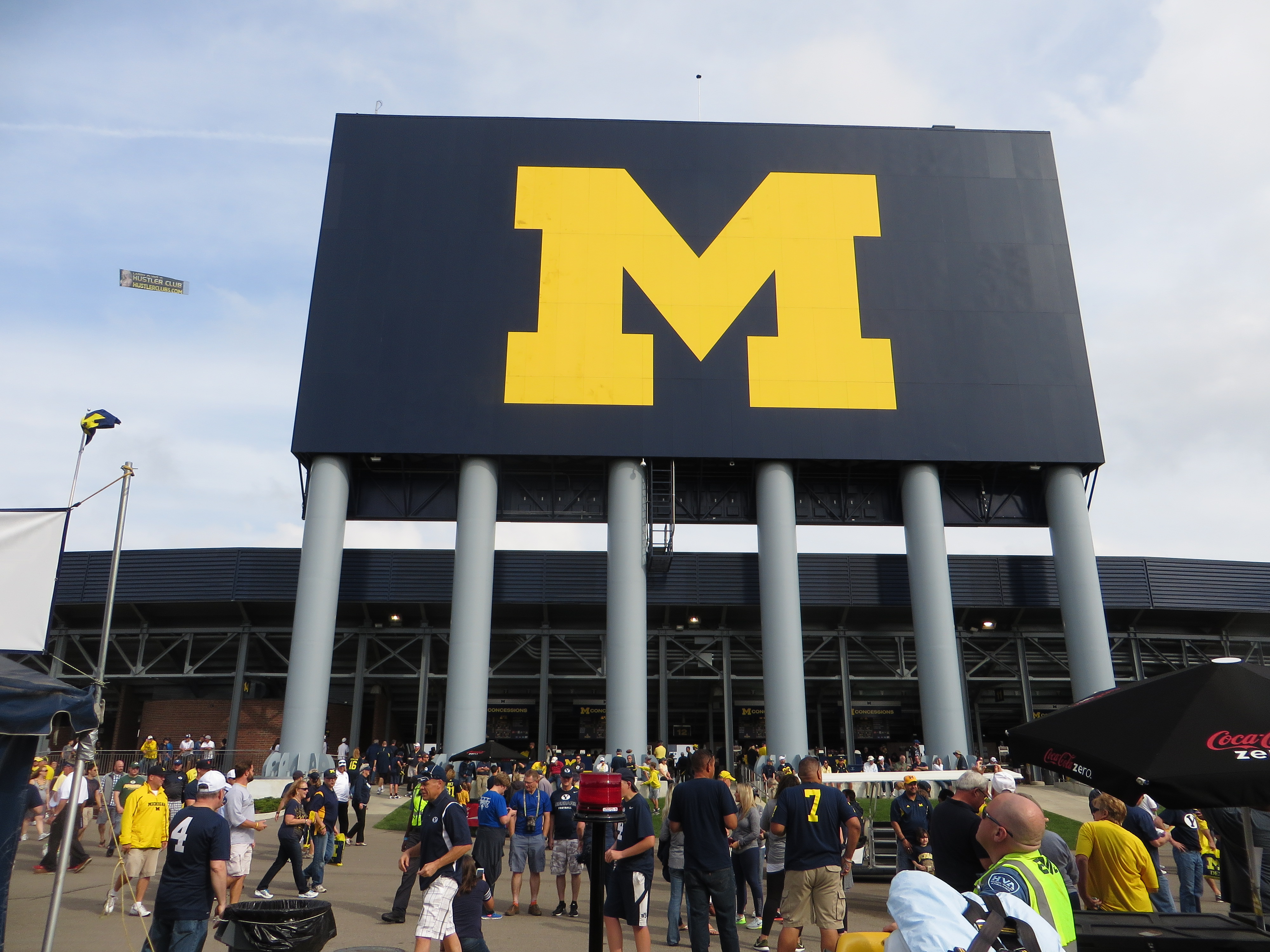 Exterior of a large football stadium with a block M logo on the scoreboard.