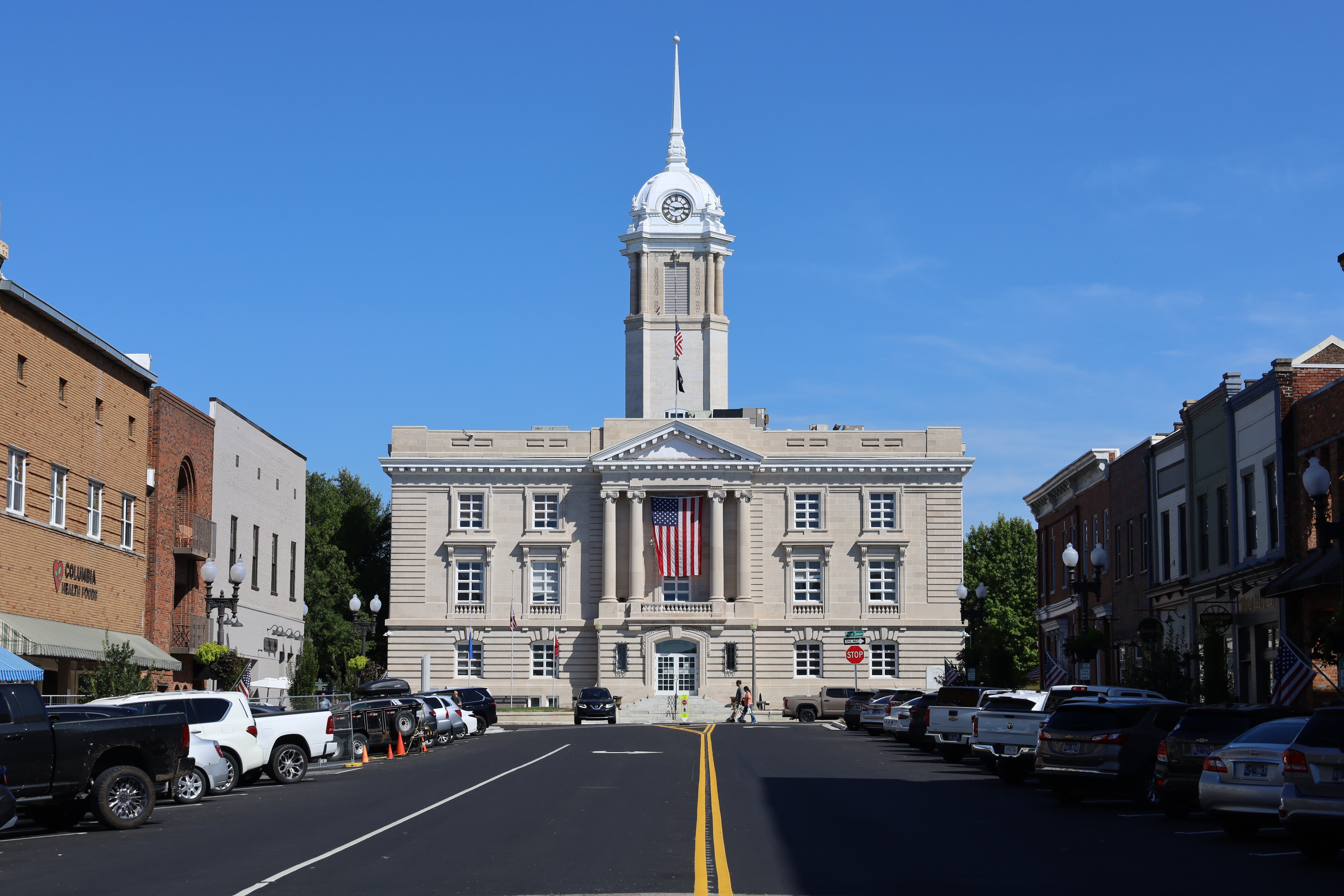 Neoclassical courthouse with white clock tower at the end of a downtown street.