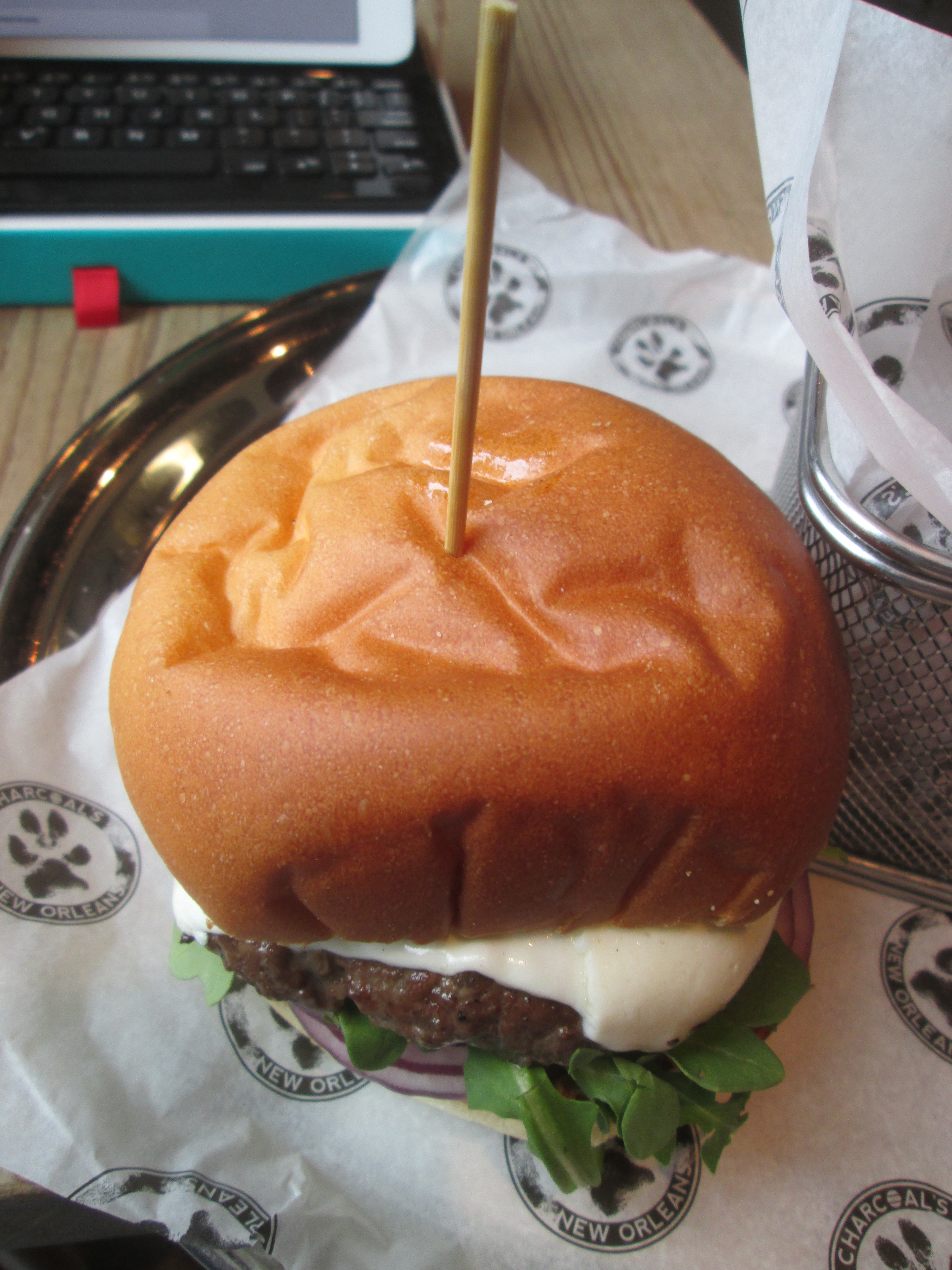 A stacked burger on a toasted brioche bun served on a metal tray.