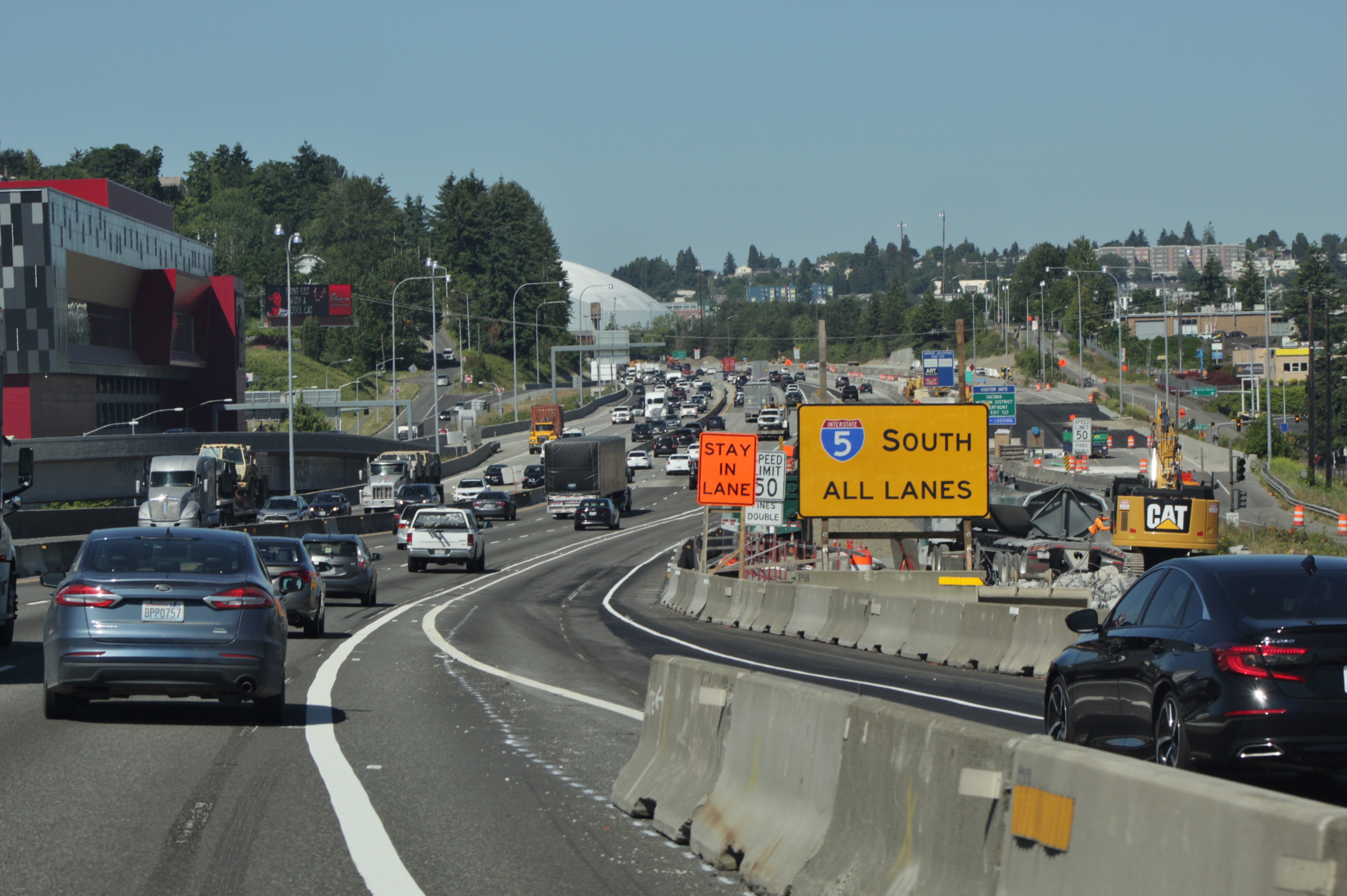 Vehicles travel southbound on Interstate 5 near Tacoma with construction barriers and highway signs visible.