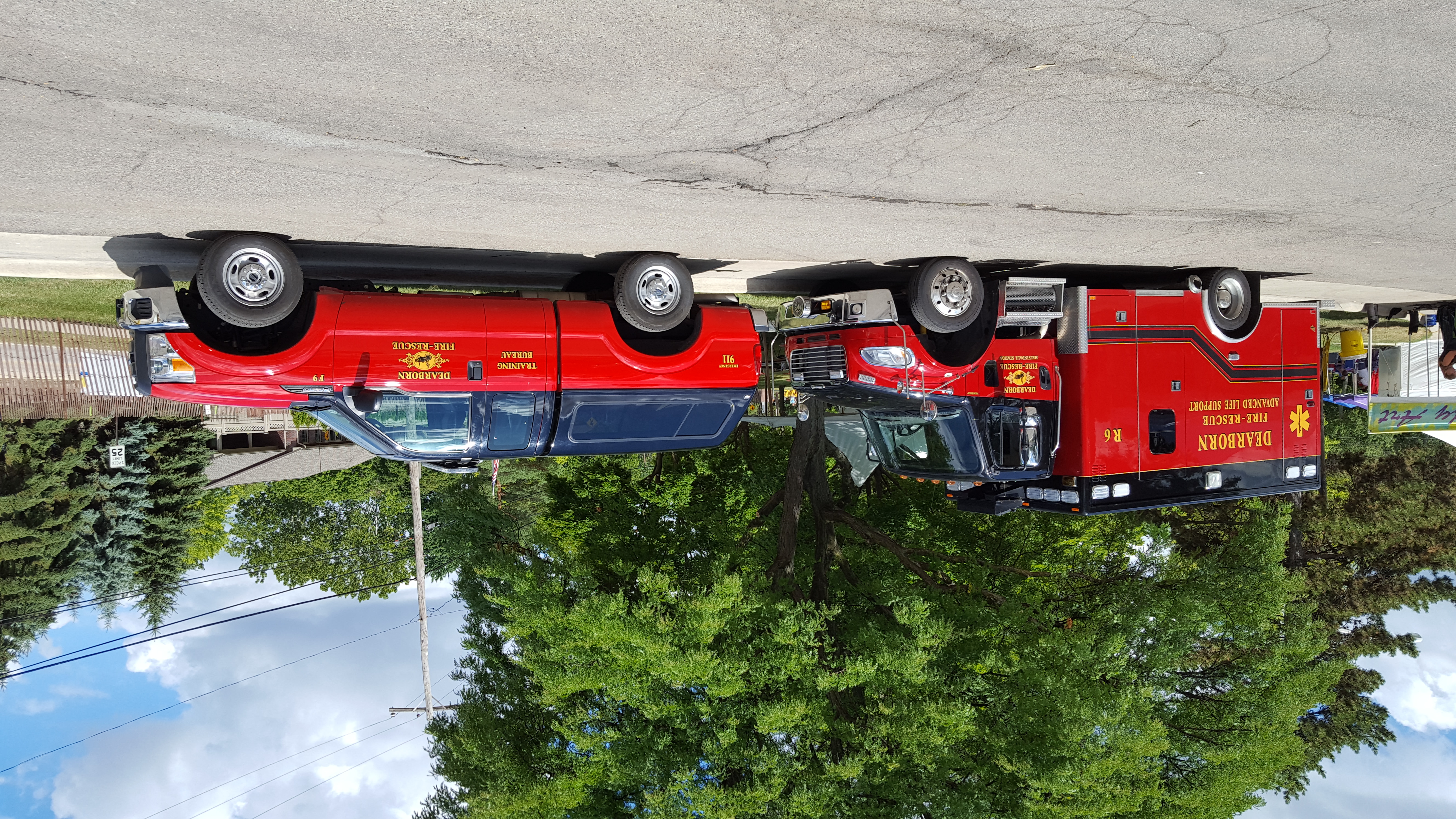 Two red fire department vehicles, including a rescue ambulance, parked in a suburban lot.