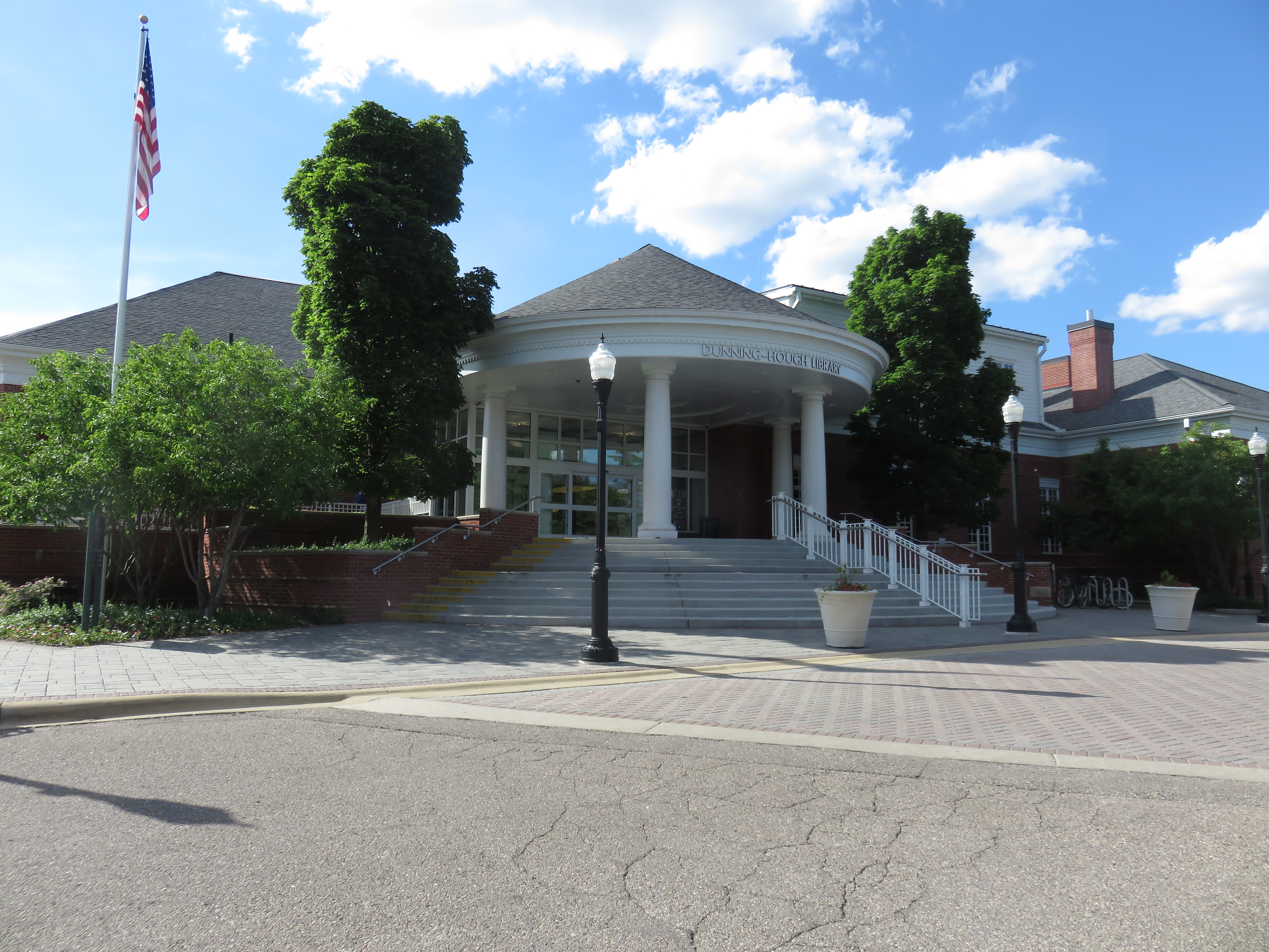 Neoclassical library building with white columns and a flagpole under a blue sky.