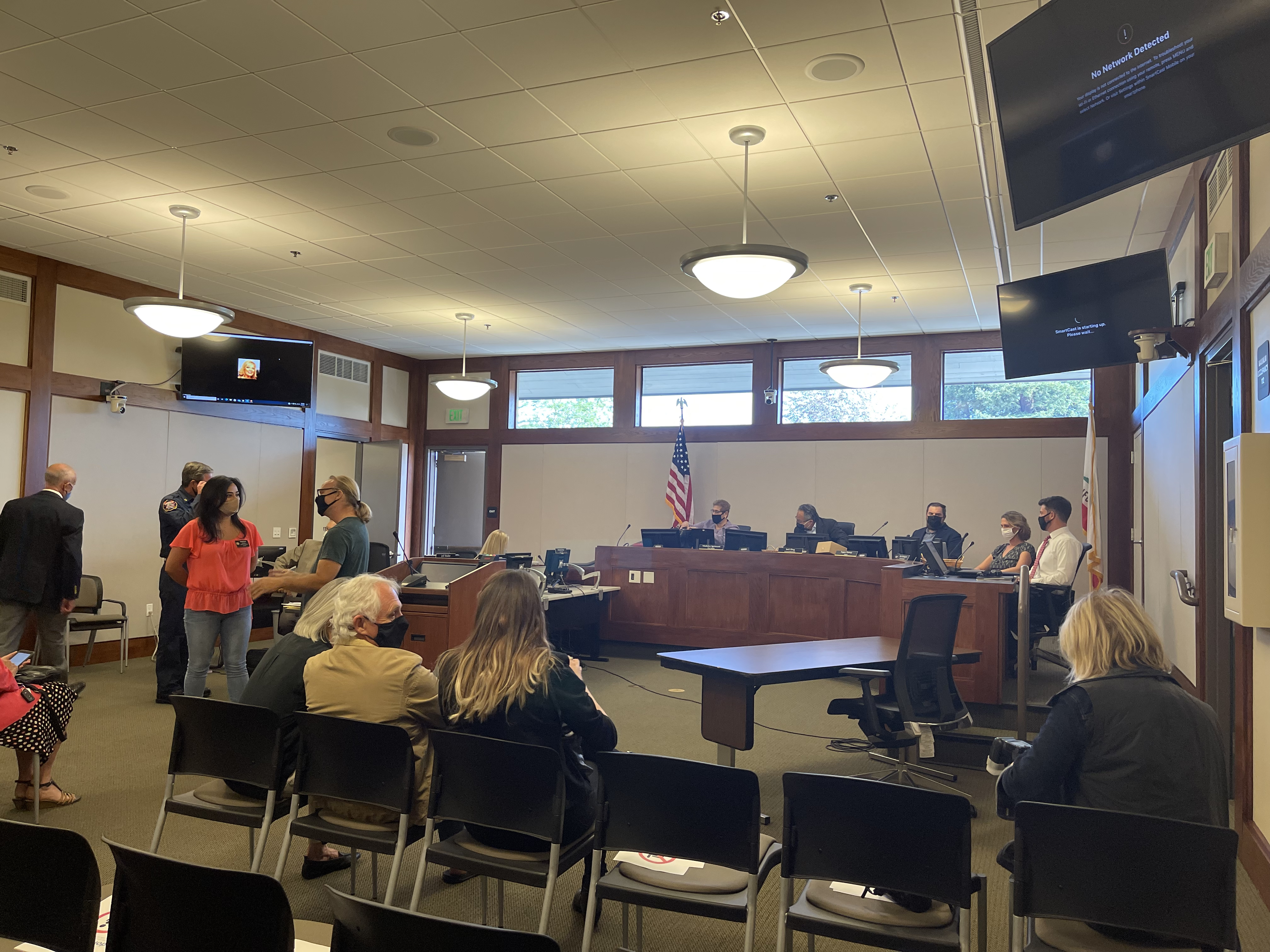 Council members seated at a raised wooden dais inside a California city council chamber.