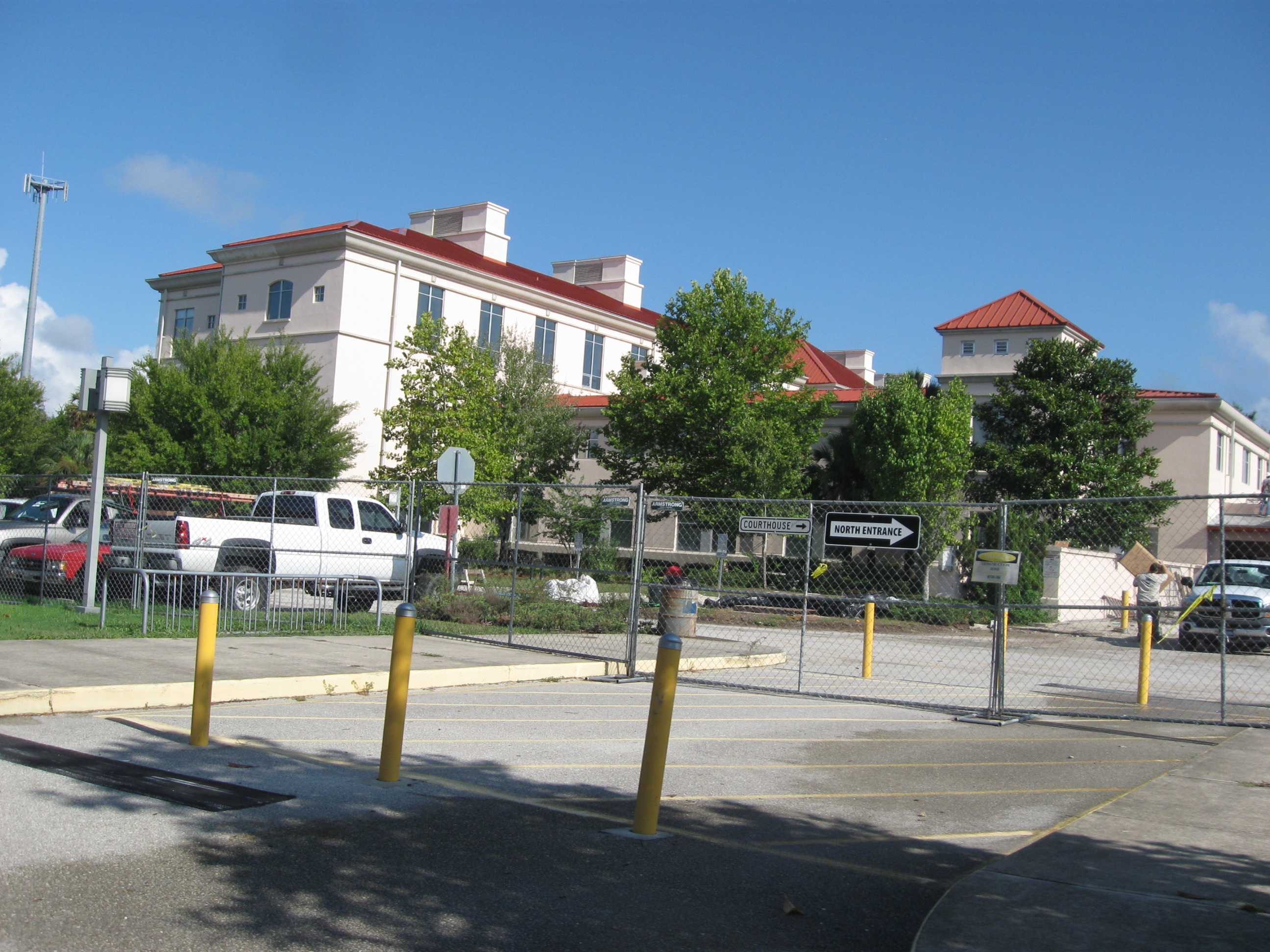Multi-story government courthouse with red roof and cream exterior, surrounded by trees.