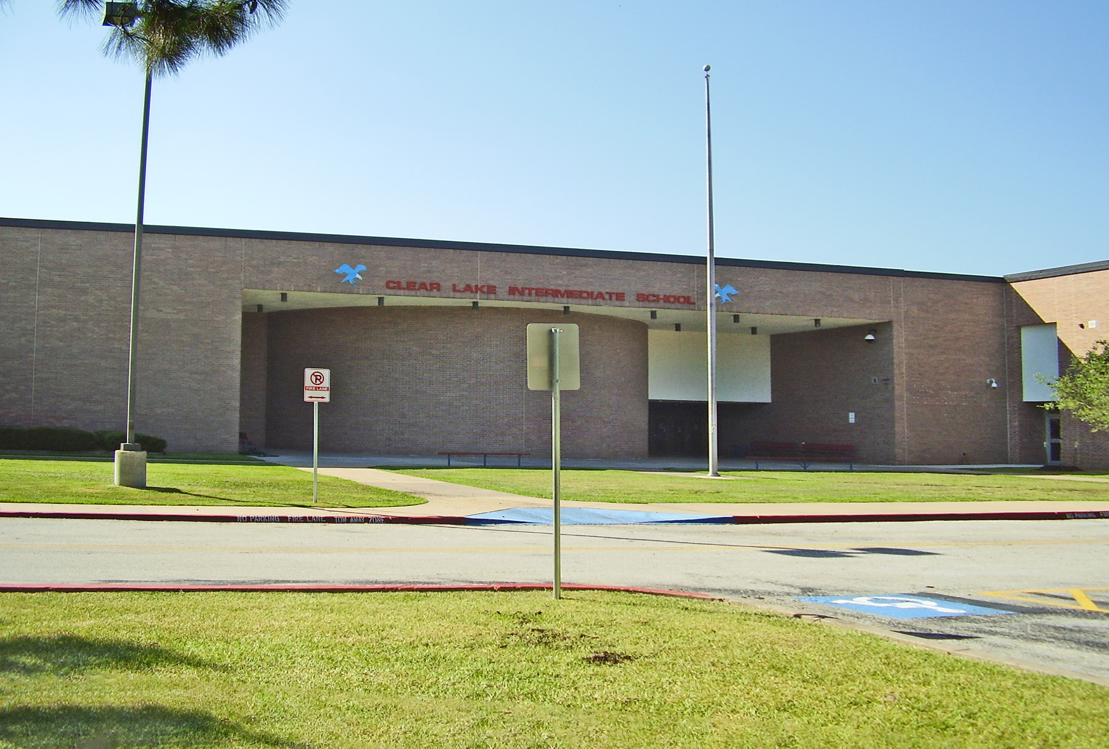 Single-story brick school building with two flagpoles and a covered entrance.