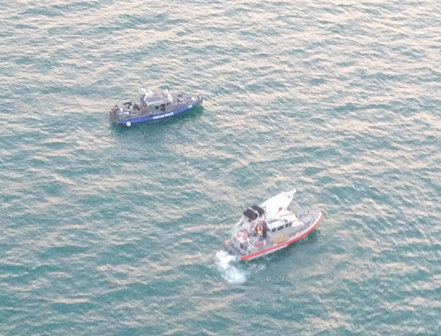 Aerial view of two rescue boats maneuvering on open water.