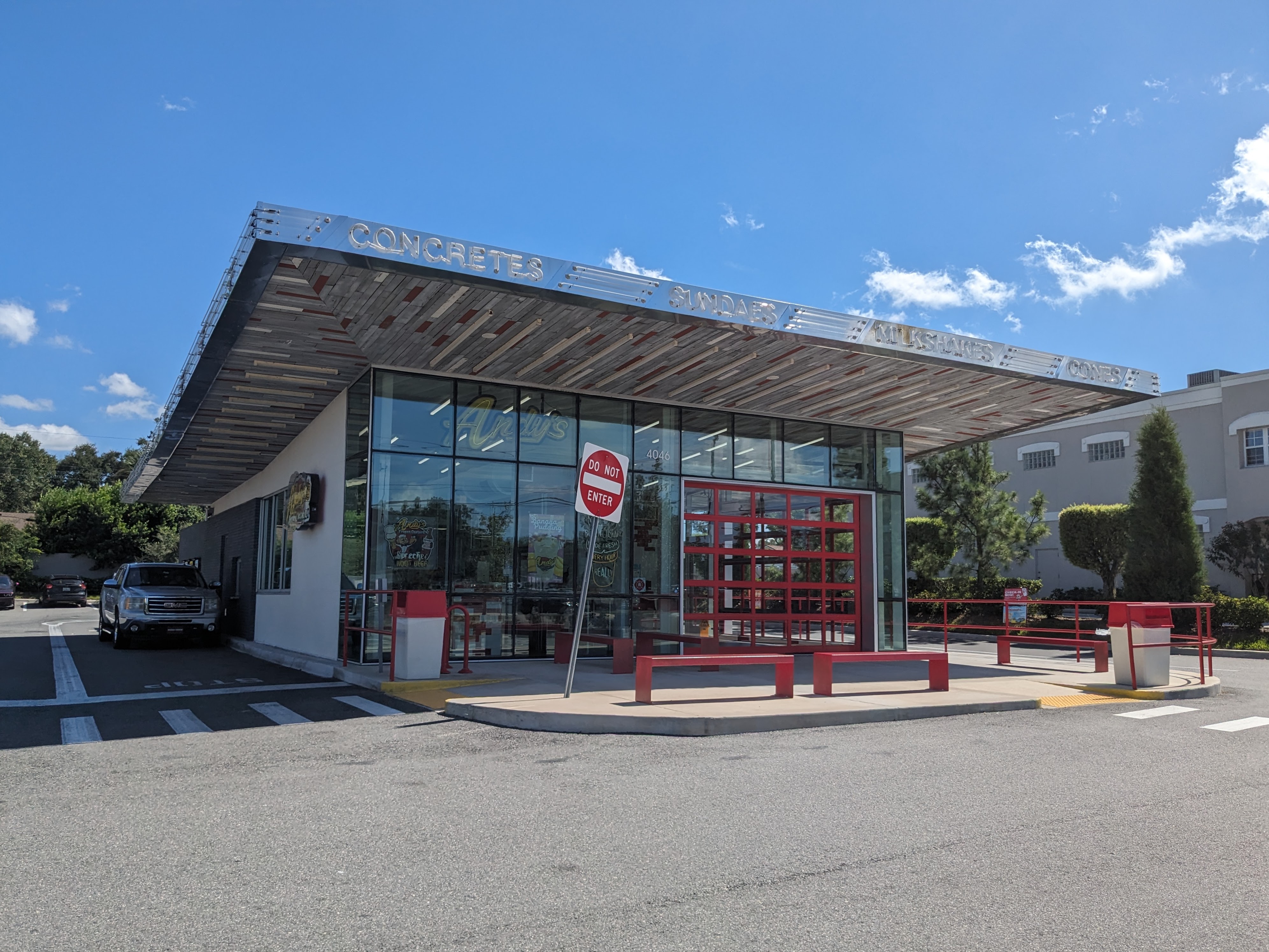 Modern glass-fronted drive-through frozen custard restaurant with red accents and wide roof overhang.