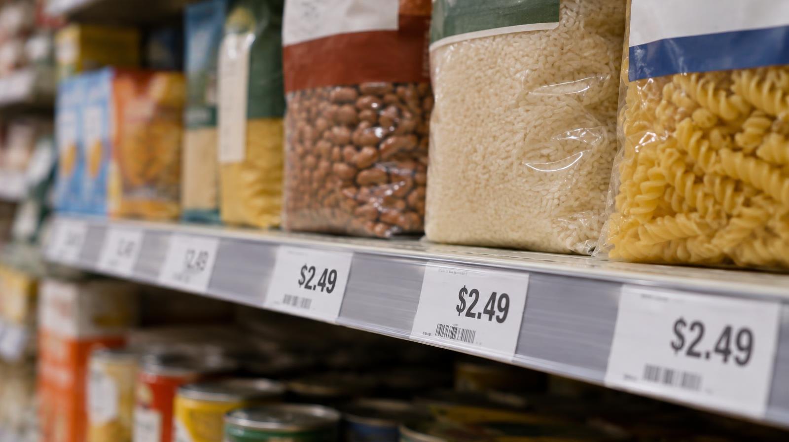 Packaged food products on a supermarket shelf with price tags under bright store lighting.