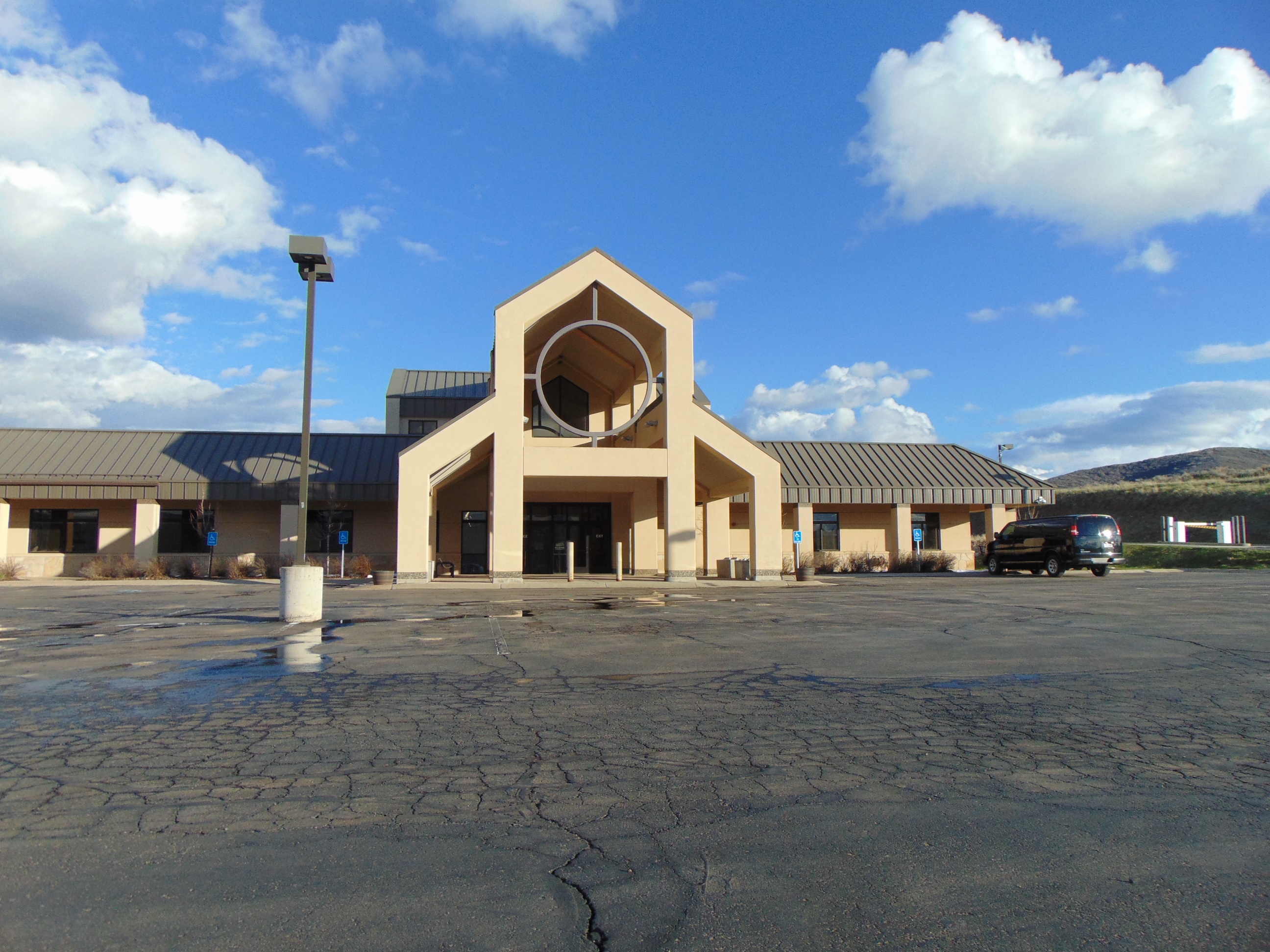 Tan single-story courthouse building with a circular entrance feature and a large parking lot.