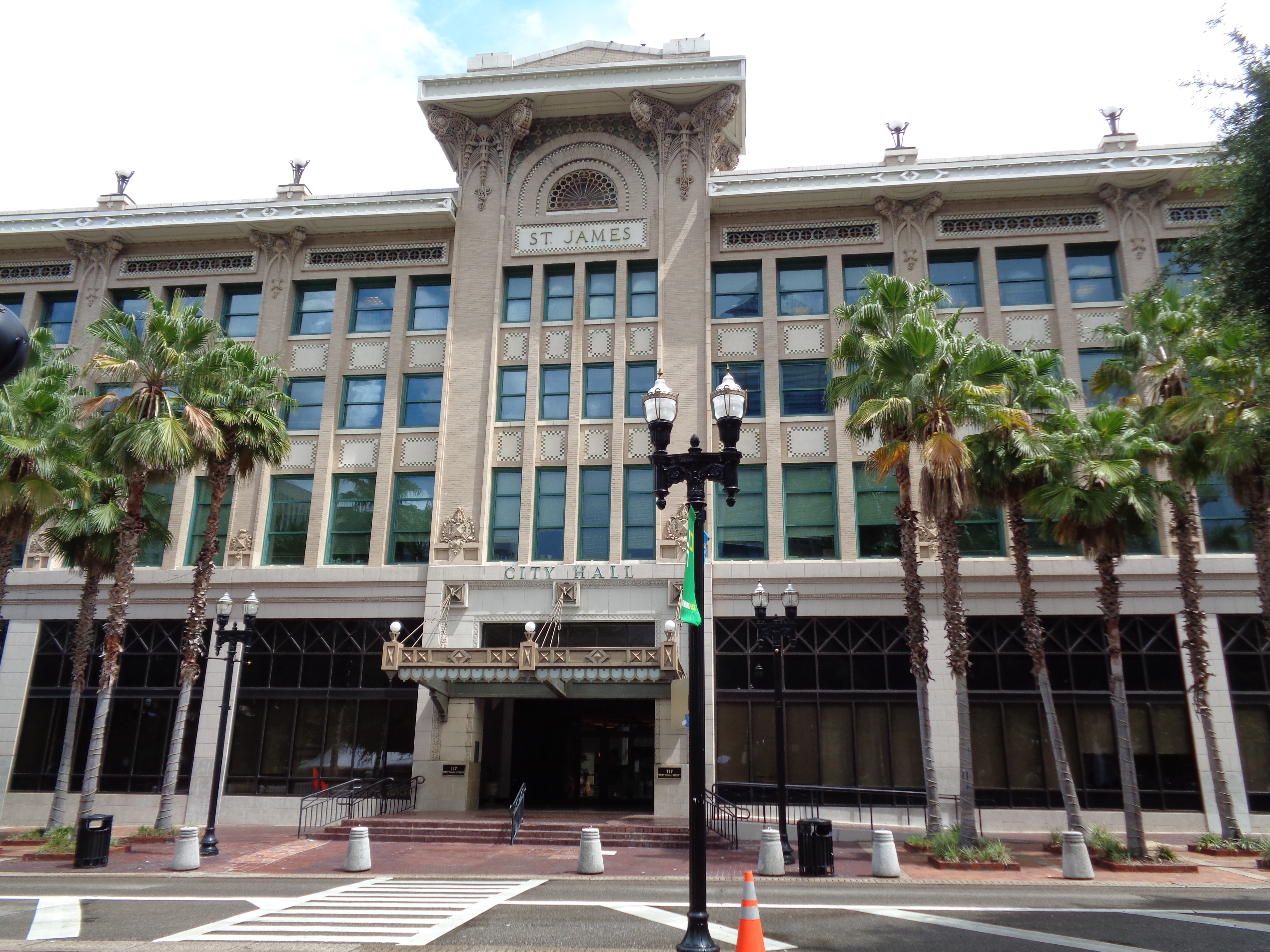 Beaux-Arts city hall building with 'City Hall' on facade, flanked by palm trees.