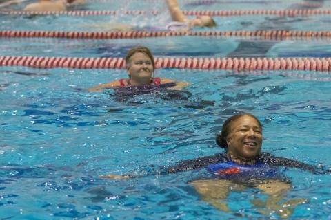Two women swimming in an indoor lap pool with lane dividers.