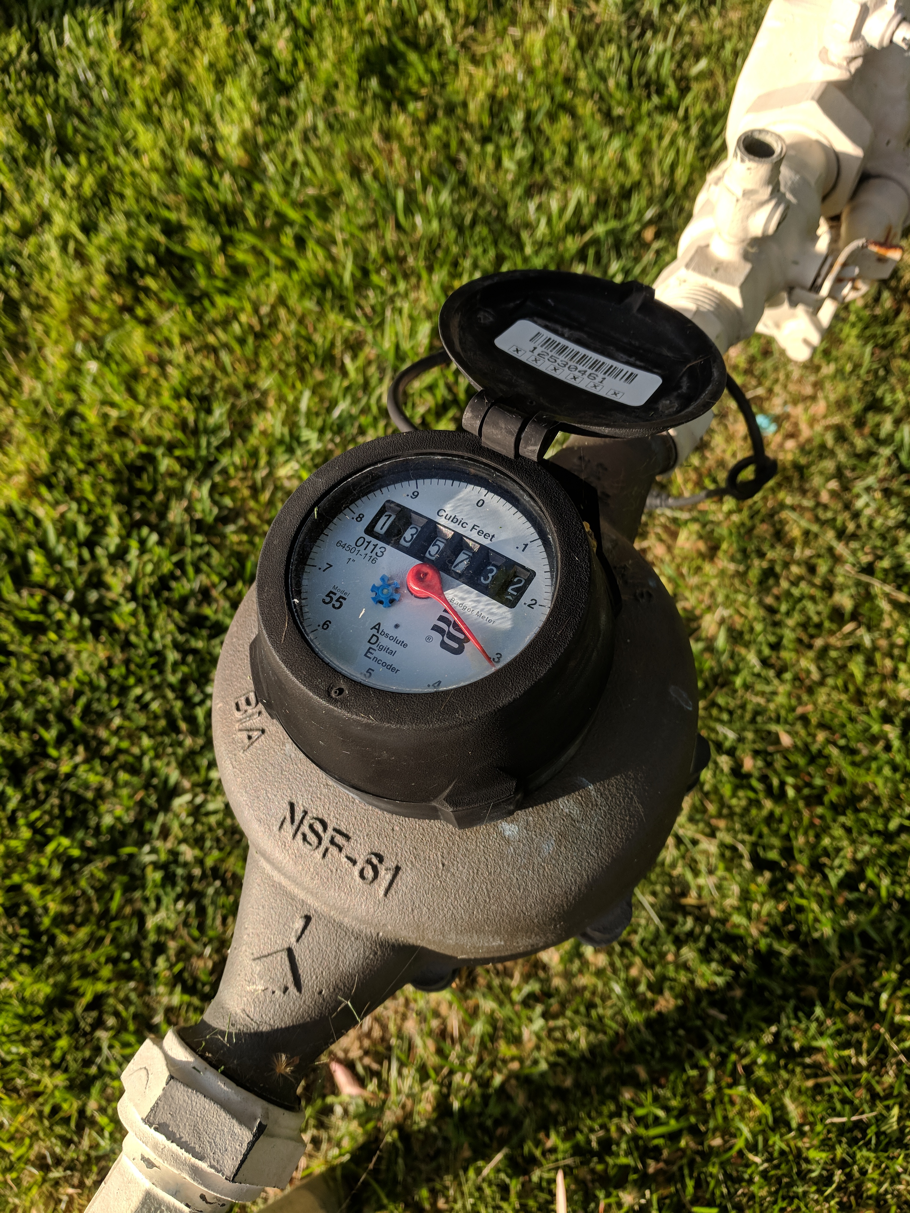 A natural gas meter mounted on a pipe in a residential lawn.
