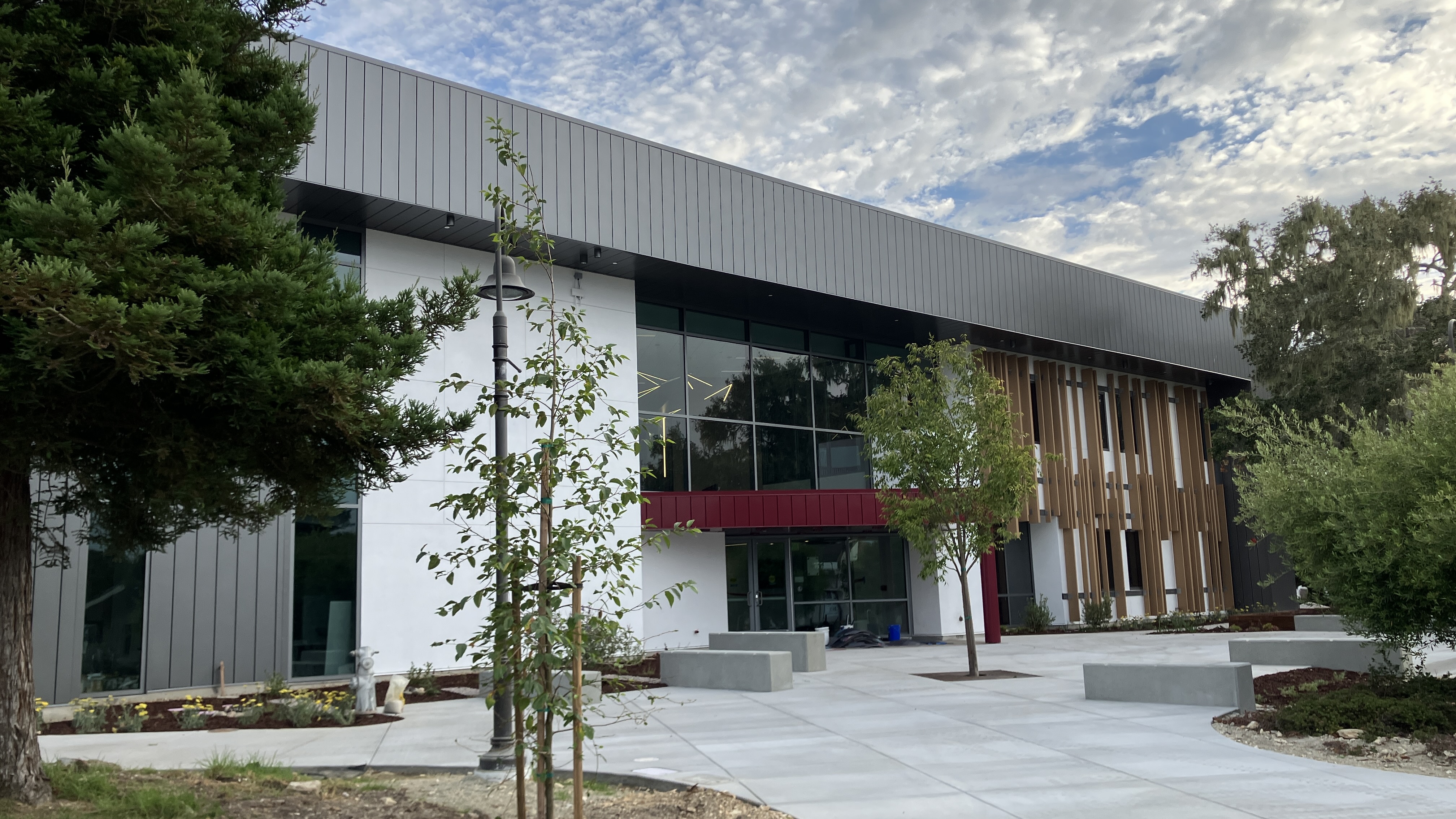 Modern two-story college building with glass windows and a concrete plaza.