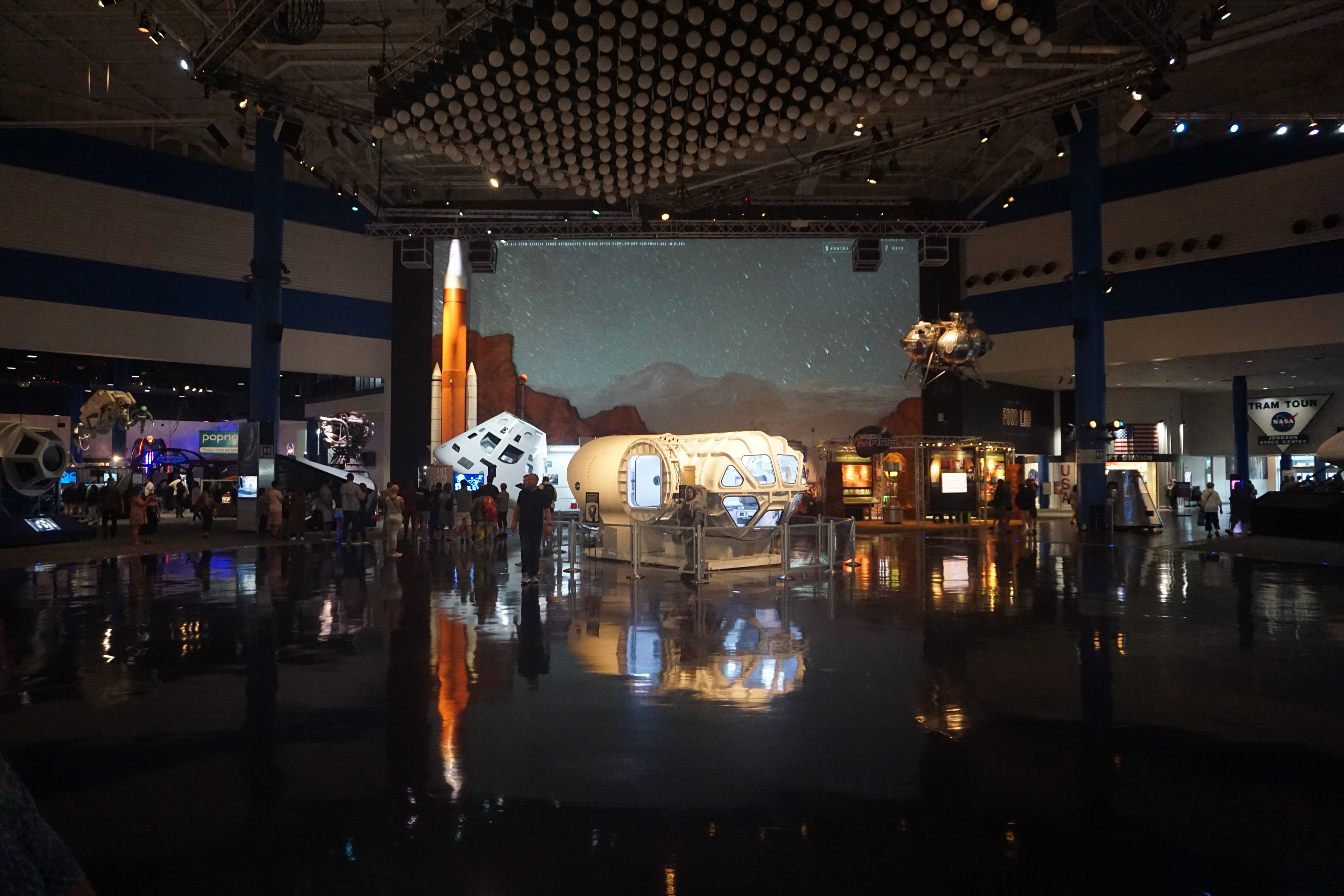 Interior of Space Center Houston with space exhibits, a Mars projection screen, and visitors.