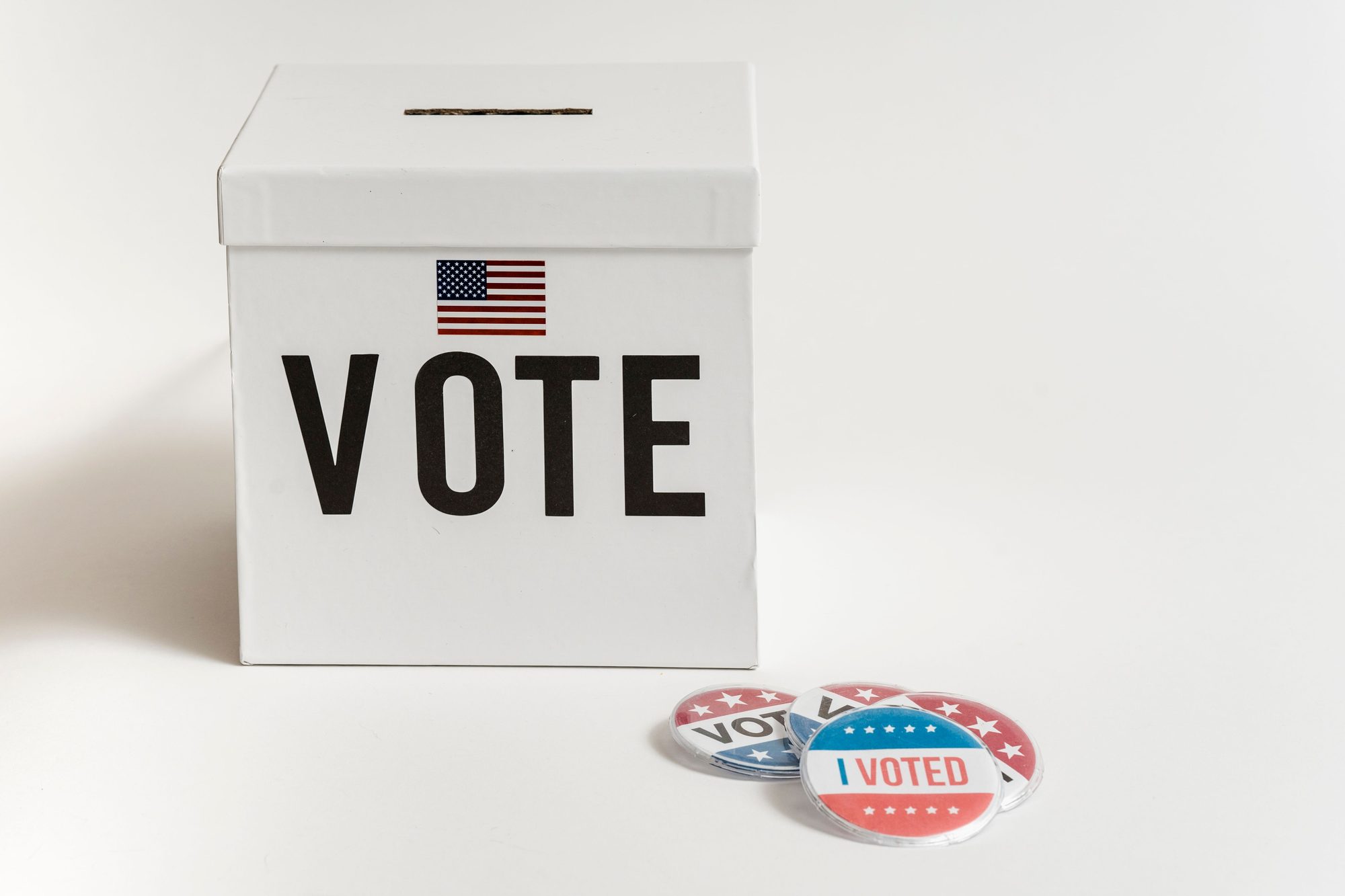 White ballot box with USA flag and 'I Voted' badges on a white background.