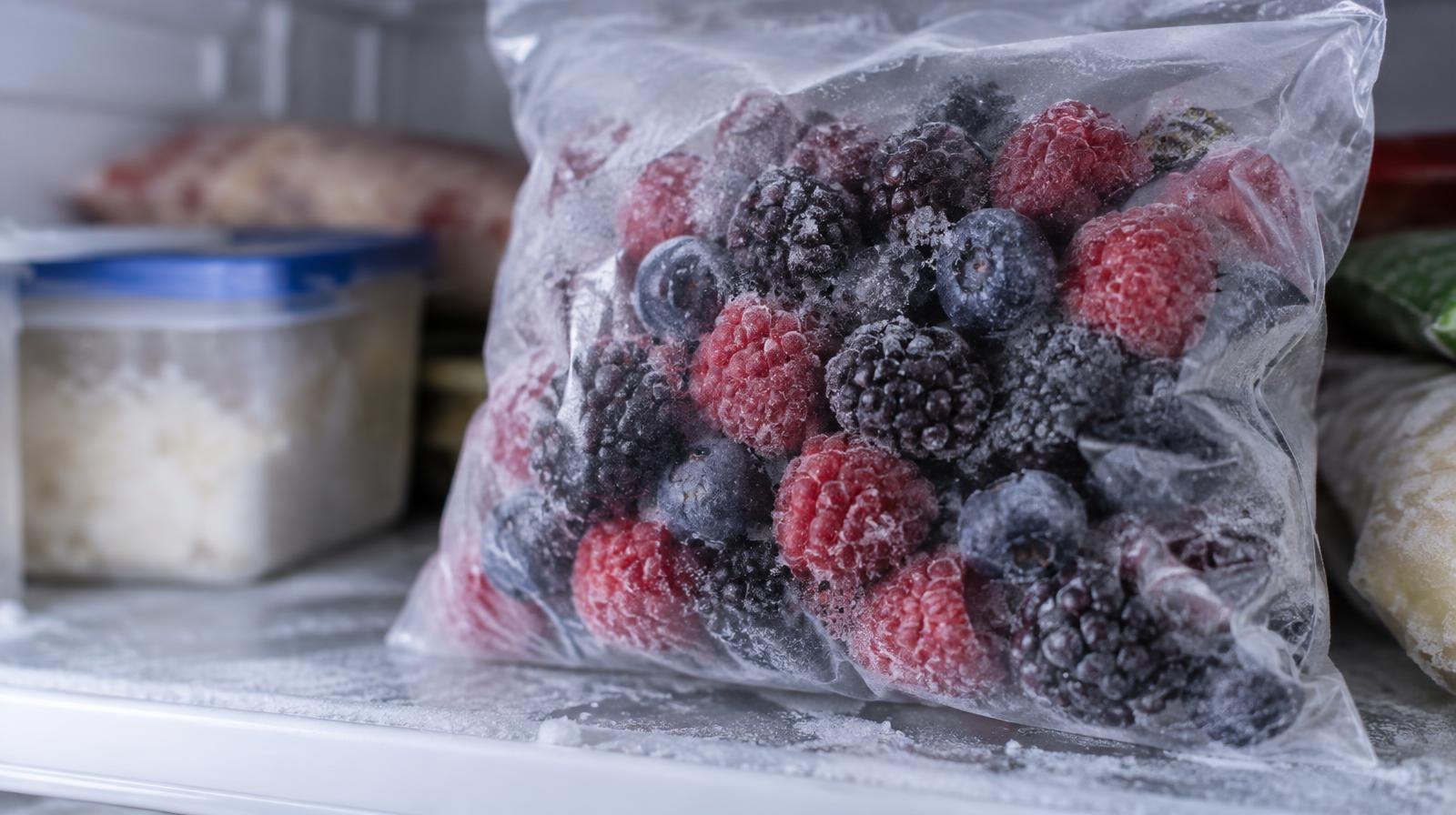 Sealed bag of frozen mixed berries resting on a frosted freezer shelf.
