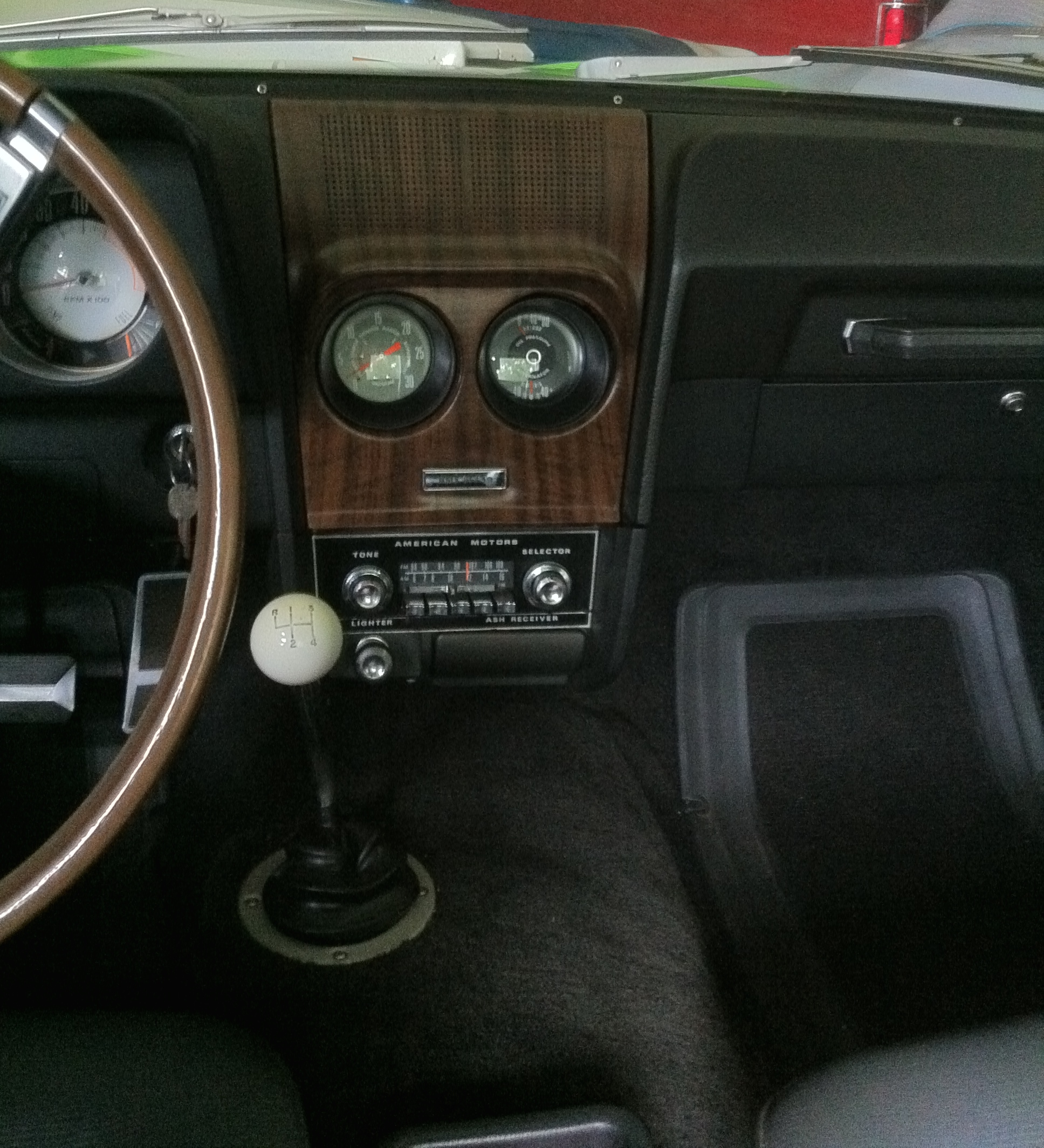 Vintage car dashboard with a factory-installed AM radio unit and gauges.