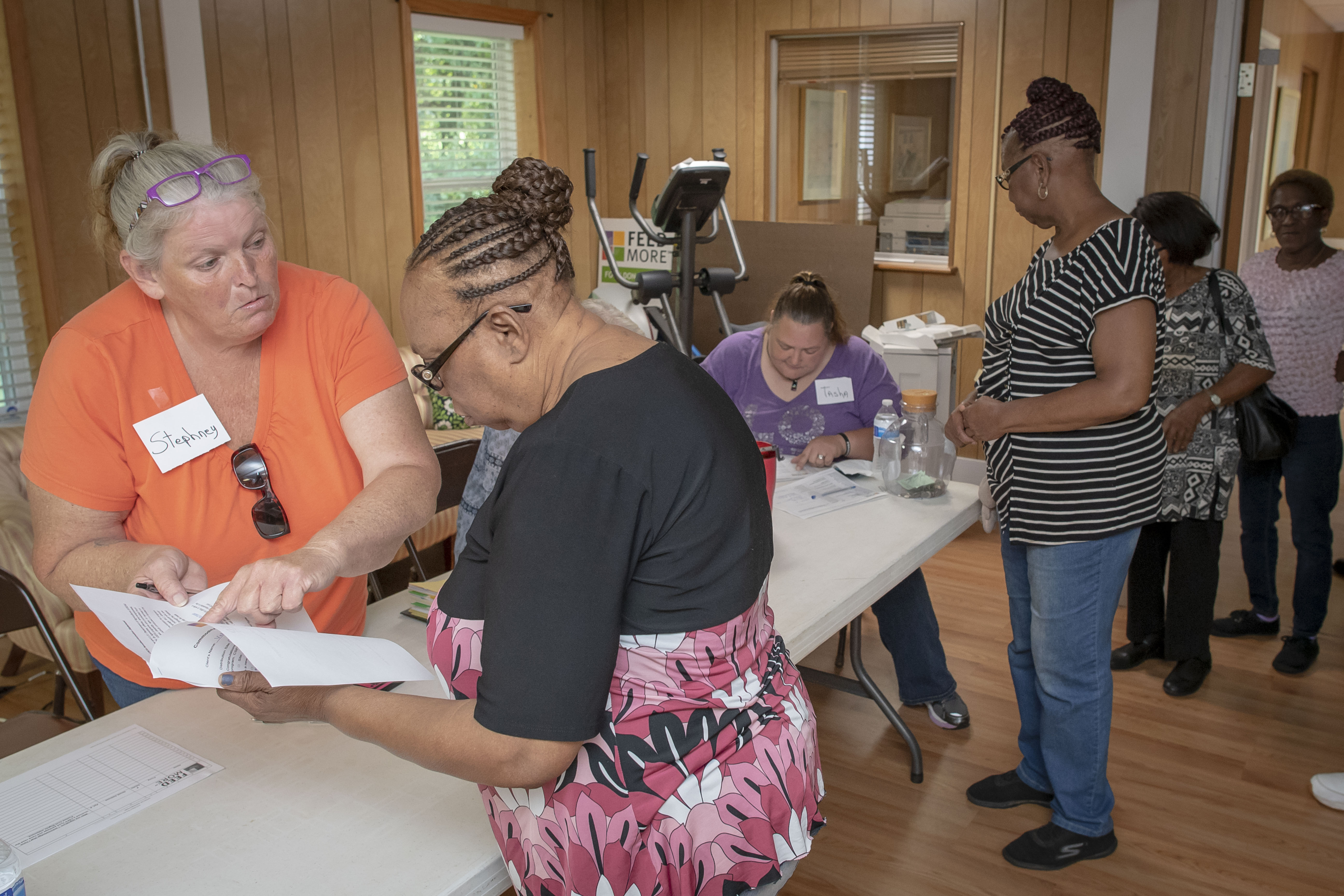 Volunteers check in participants at a table inside a community food pantry.