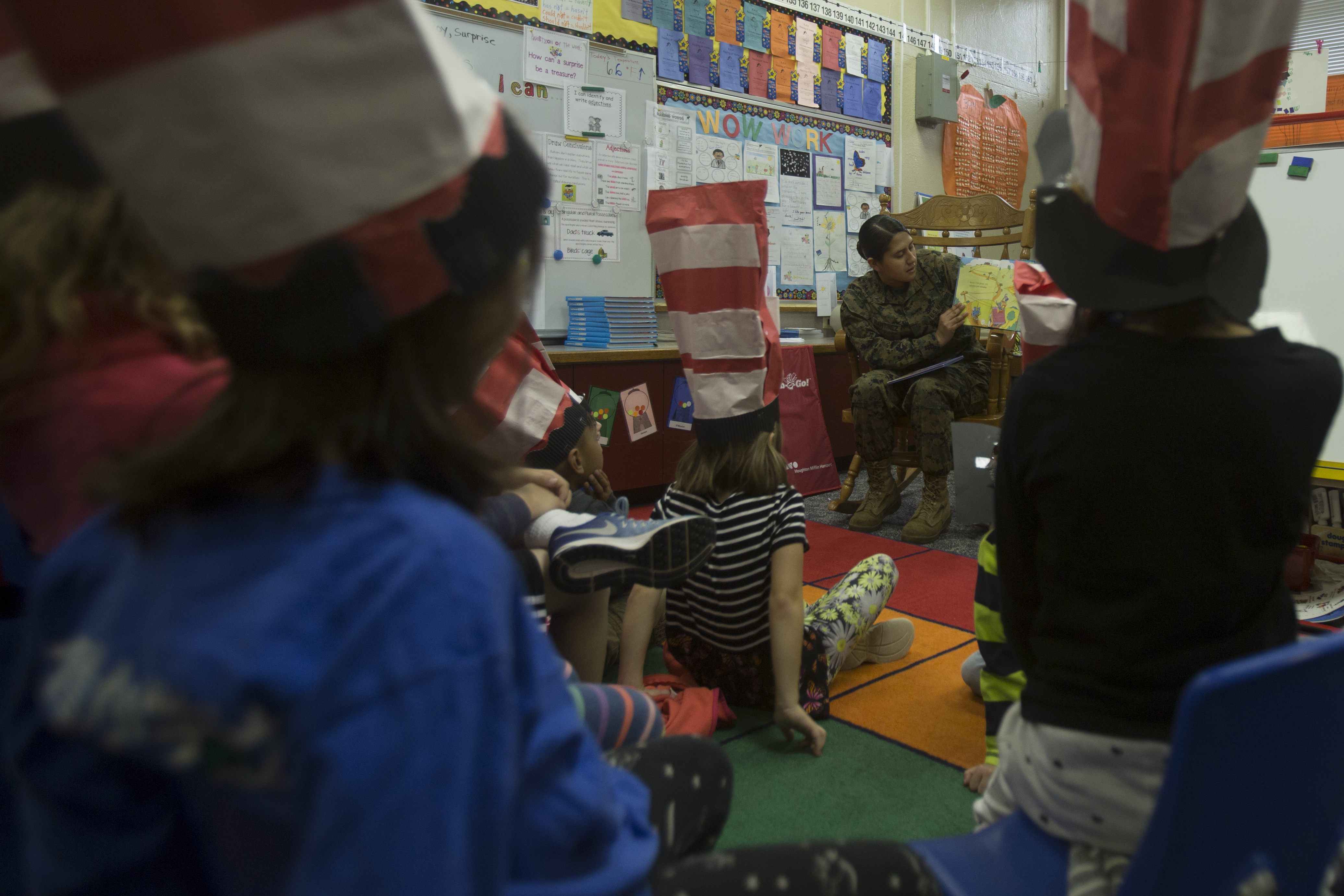 An adult reads a picture book aloud to young children seated on a classroom floor.
