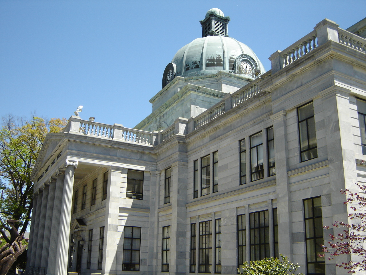 Neoclassical stone courthouse with a green copper dome and white columns against a blue sky.