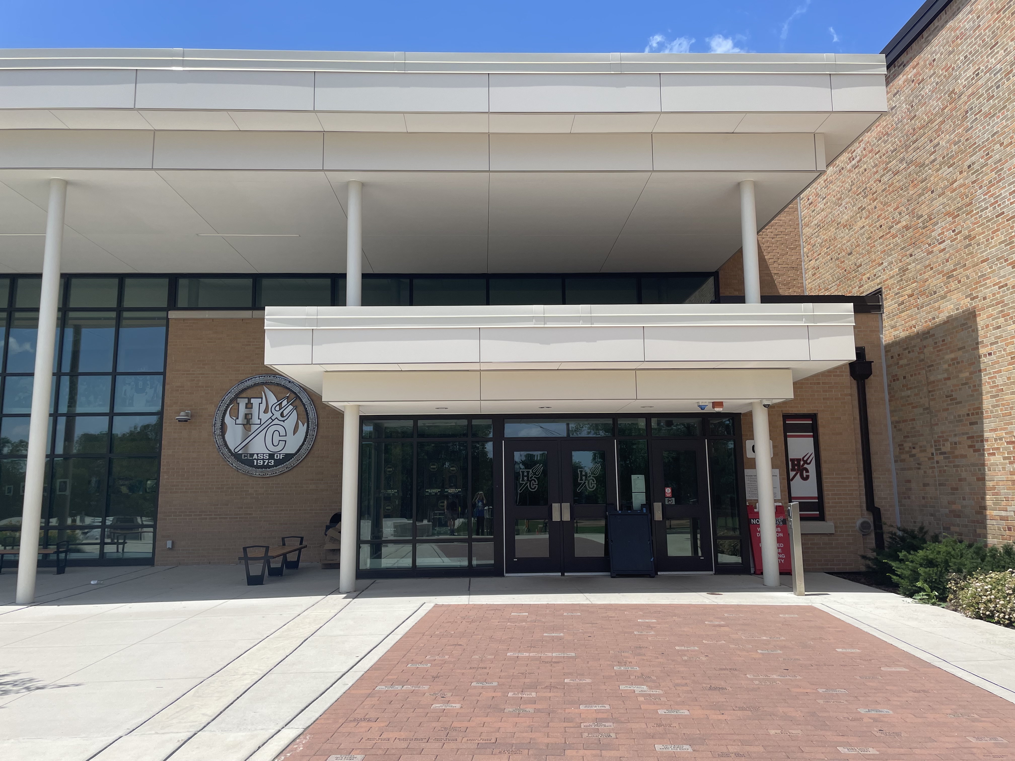 Main entrance of a brick high school building with white columns and a circular school emblem.