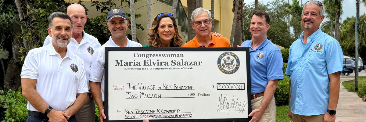 Group of six people outdoors holding a large ceremonial check for stormwater improvements.