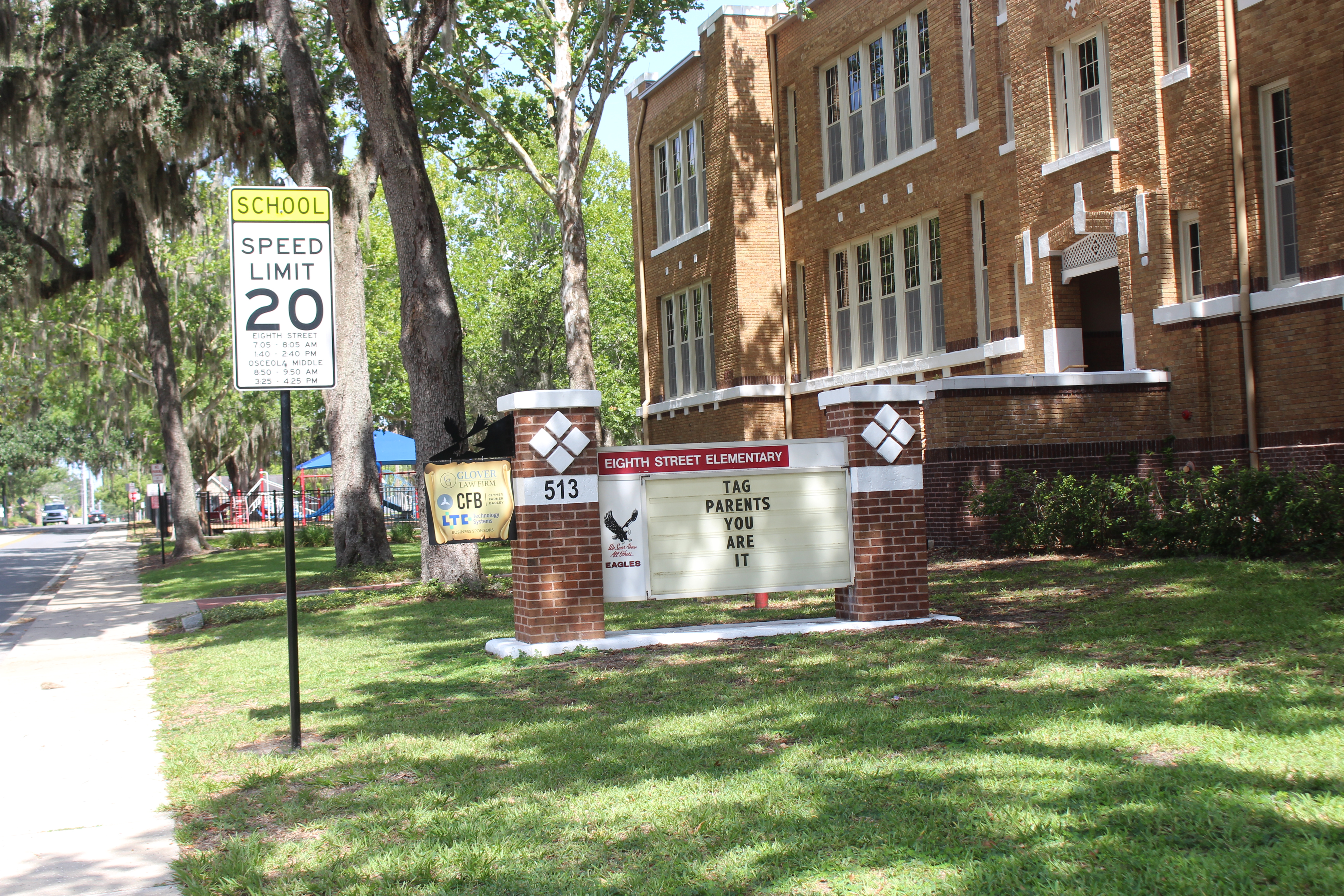 Brick elementary school building exterior with a marquee sign and school zone speed limit sign.