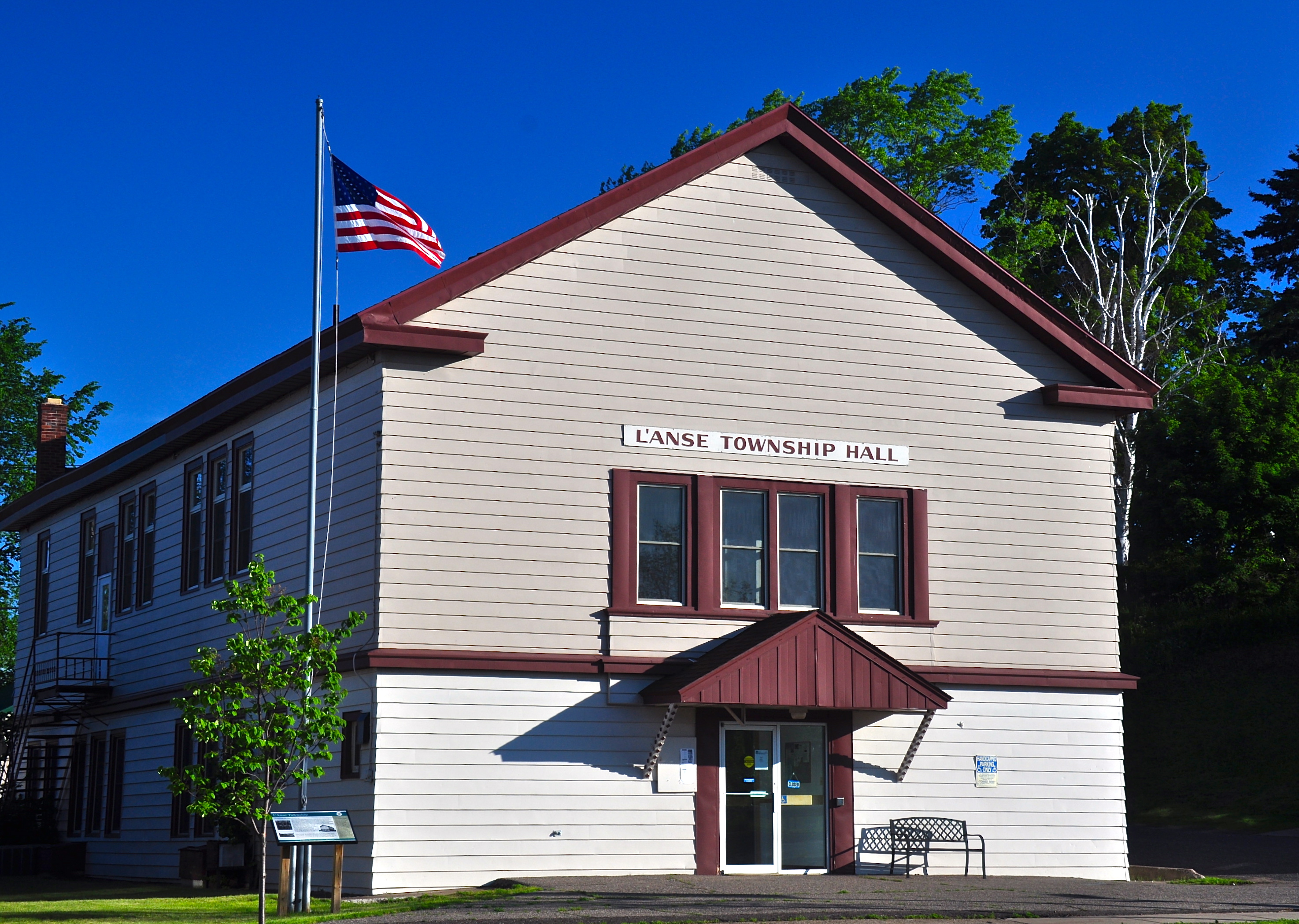 White two-story township hall building with red trim and American flag out front.