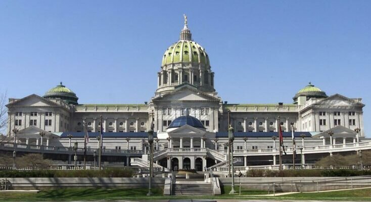 Pennsylvania State Capitol building with green dome and classical columns under a blue sky.